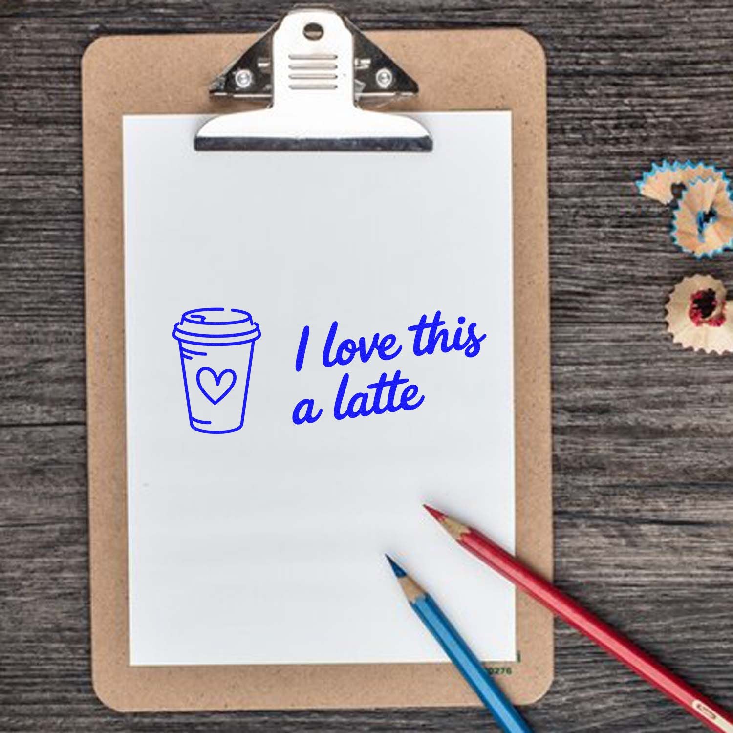 Blue coffee cup stamp and seal with I love this a latte on a white sheet clipped to a clipboard, with red and blue pencils