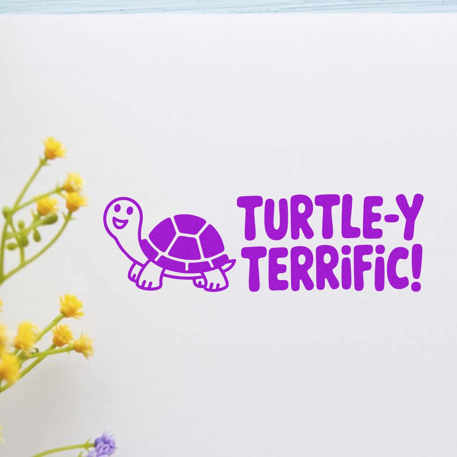 Purple turtle stamp/seal with TURTLE-Y TERRIFIC! text on white, accented by yellow flowers.