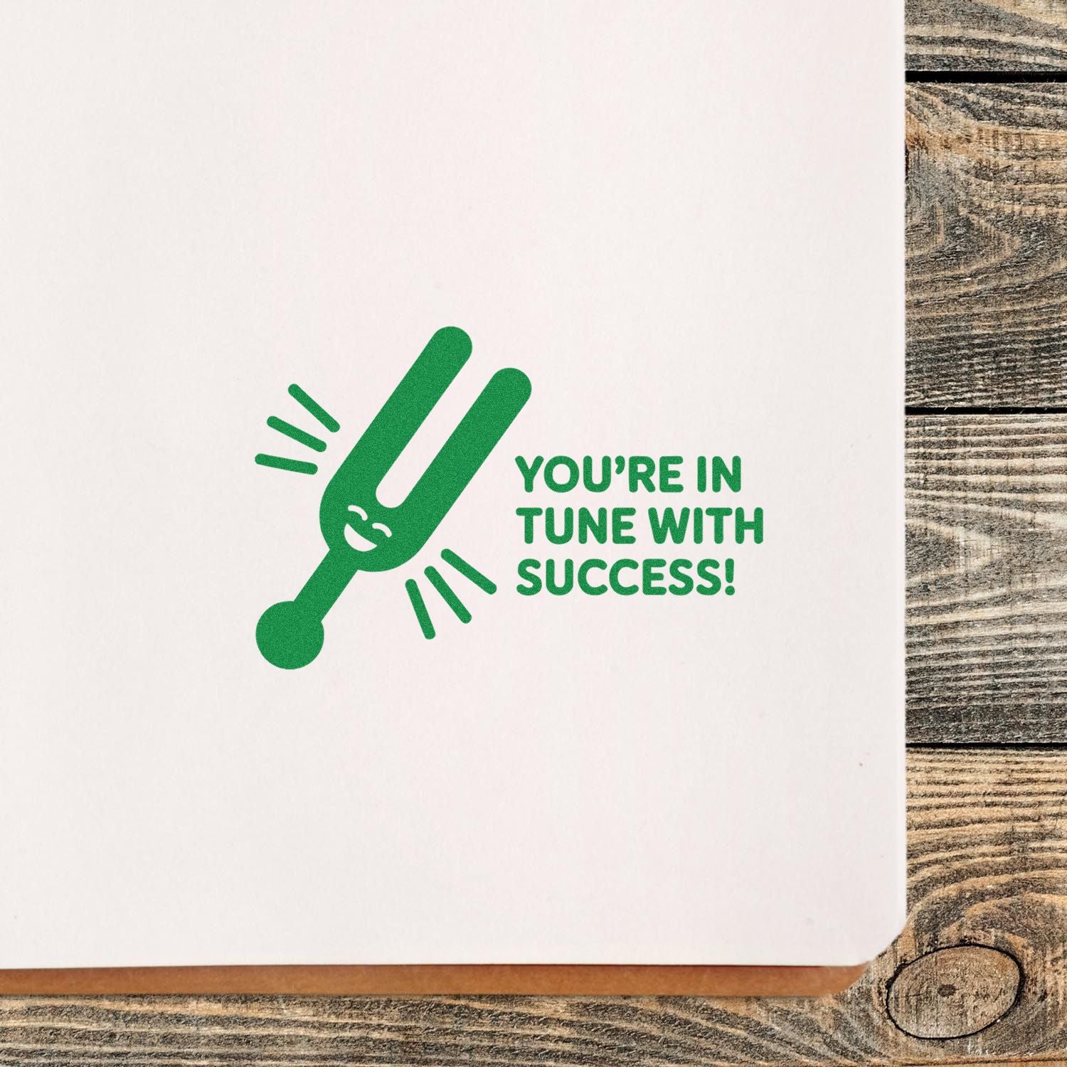 Green custom stamp seal with a tuning fork graphic and Youre in tune with success! on white paper background