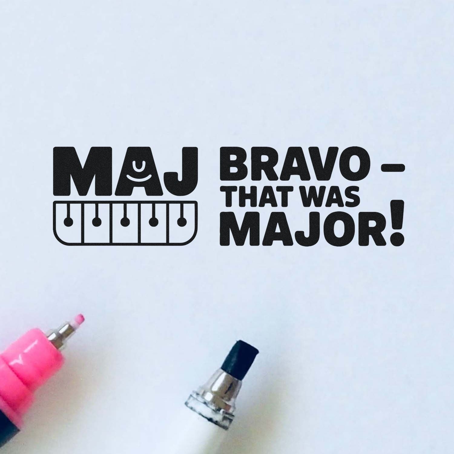 Black stamp and seal imprint reading MAJ BRAVO THAT WAS MAJOR! with pink and black self-inking stamp tools on white.