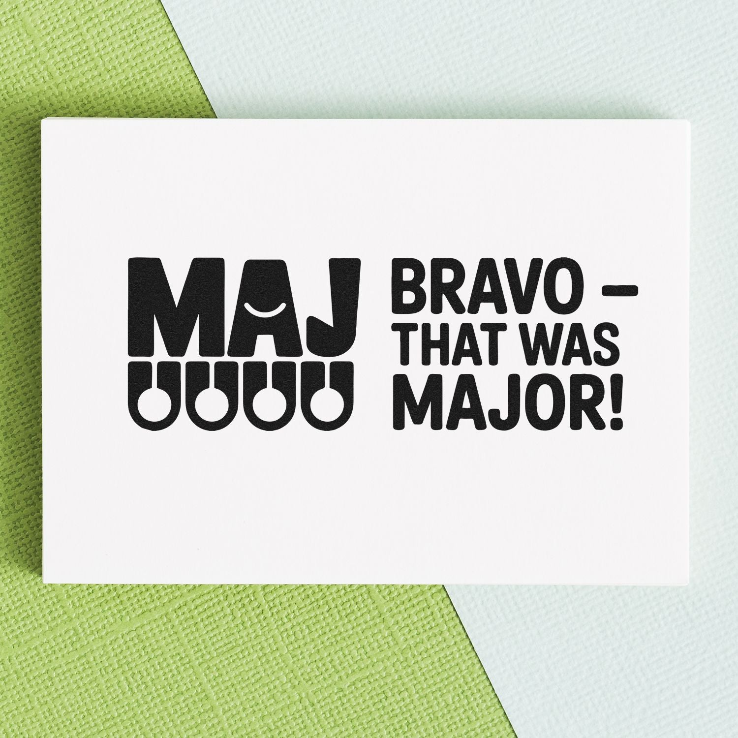 White stamp and seal card with black MAJ BRAVO THAT WAS MAJOR! text on green and pale blue textured background.
