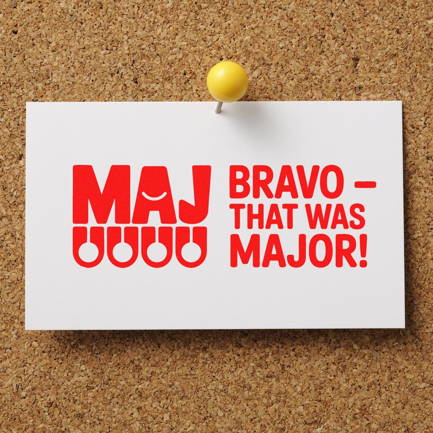 White card with red MAJ Bravo That Was Major stamp and seal design pinned to a corkboard with a yellow pushpin.