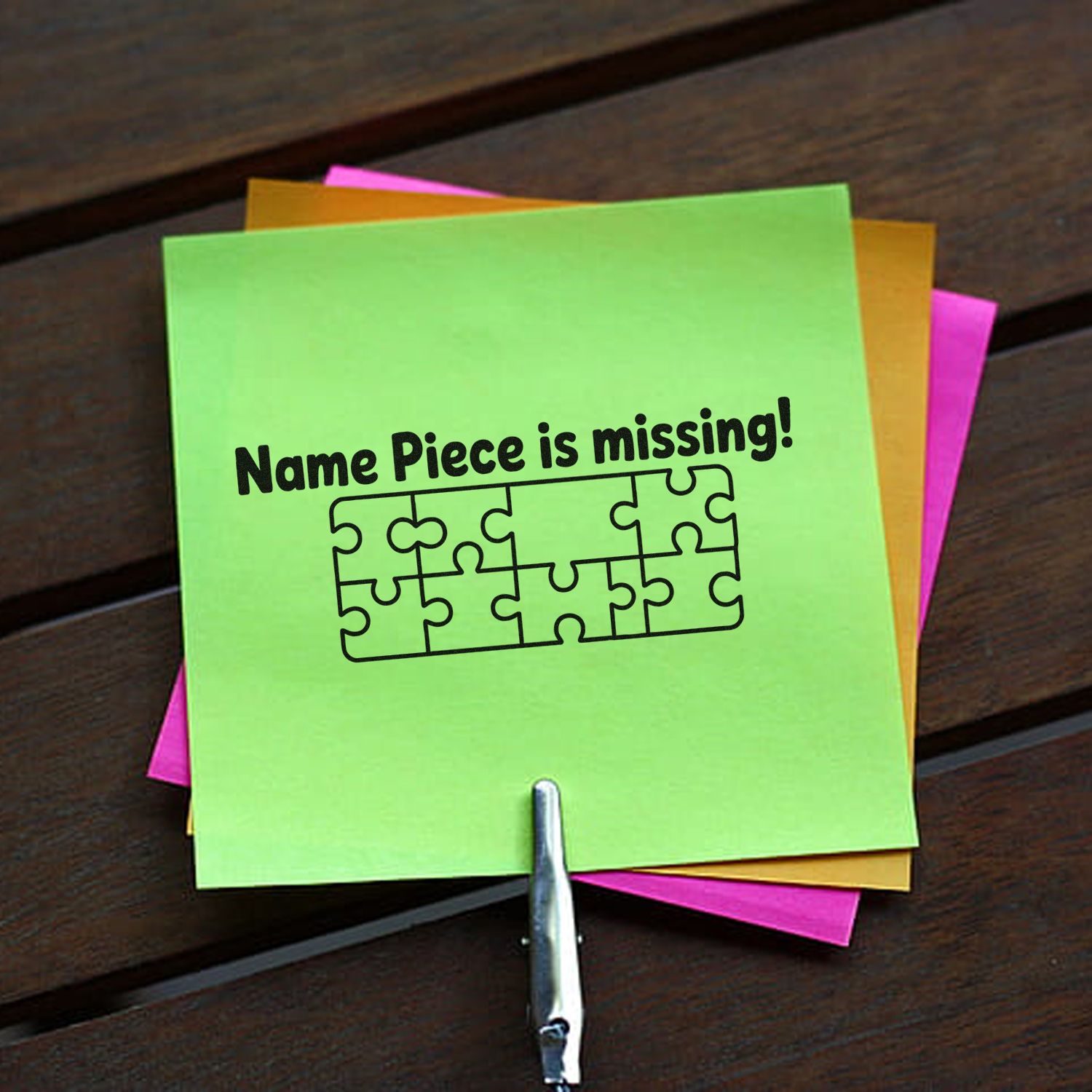 Neon green custom stamp seal with black puzzle graphic and Name Piece is missing! text, layered over pink and orange notes
