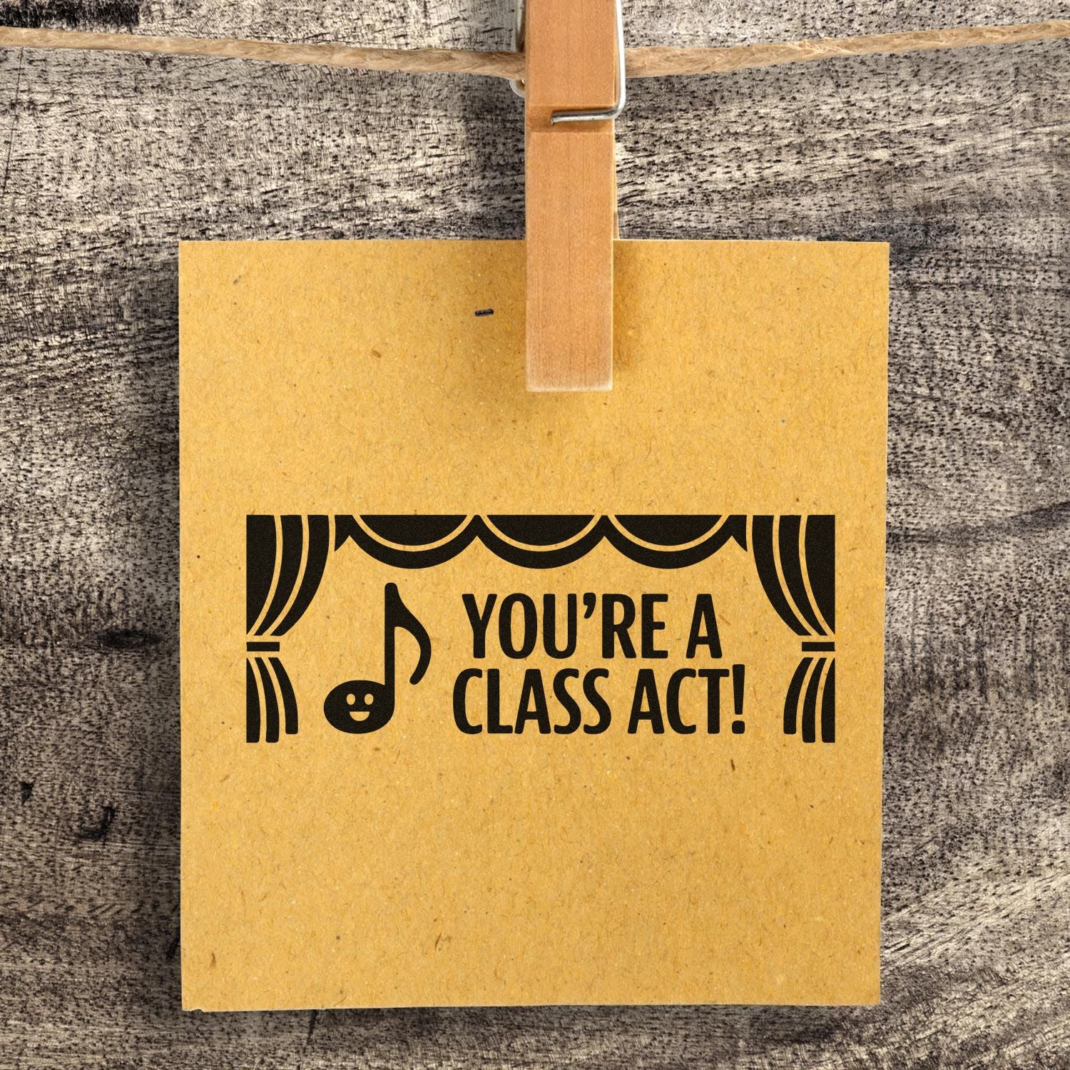 Yellow kraft tag clipped with wooden clothespin, custom stamp in black: Youre a class act! with stage curtains and music note.