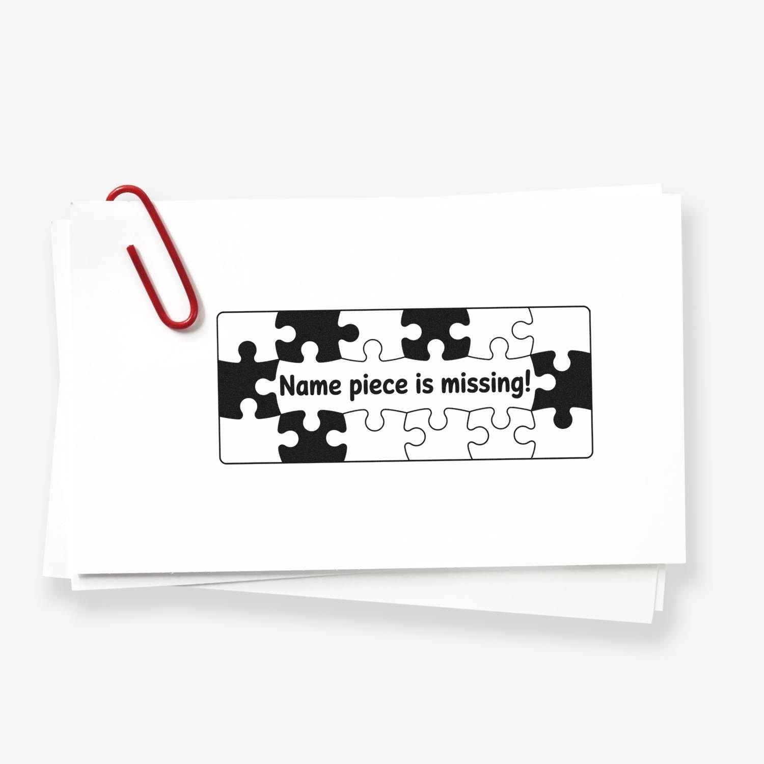 Stacked white cards with a red paperclip and black-and-white puzzle stamp seal reading Name piece is missing!
