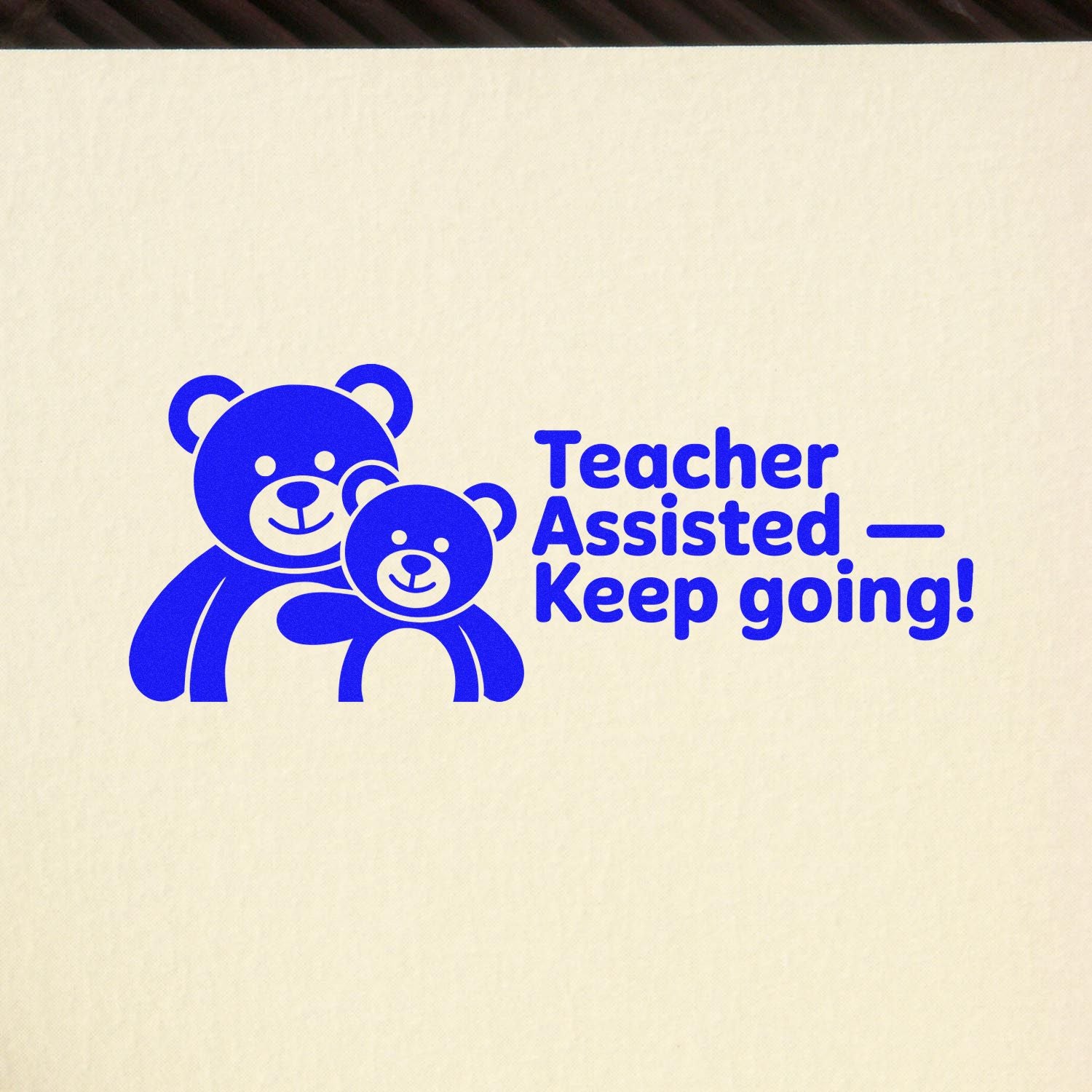 Blue teacher-assist self-inking stamp with two teddy bears and Keep going! on a cream background.