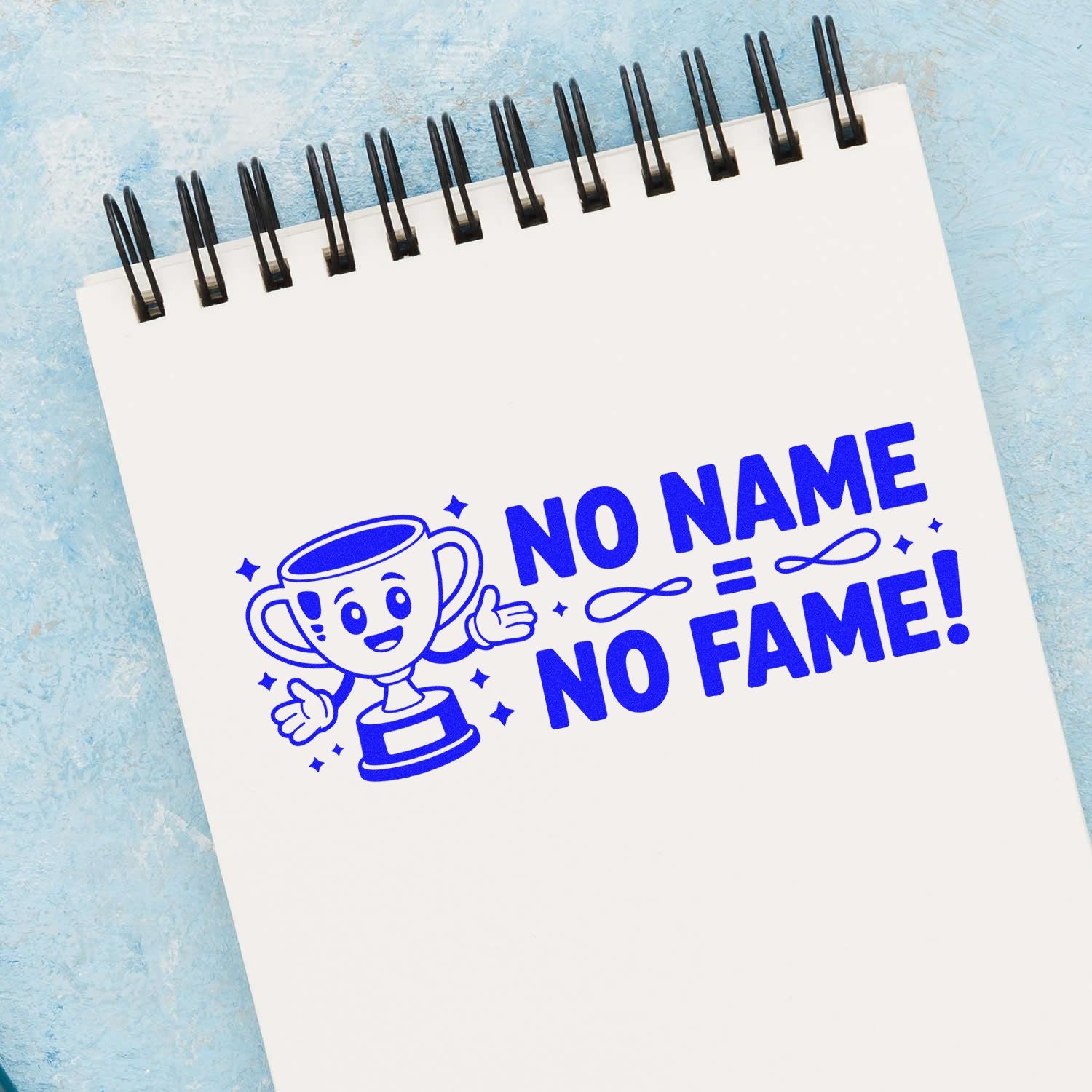 Blue custom stamp and seal design on white spiral notebook, featuring a trophy mascot and bold NO NAME NO FAME! text.