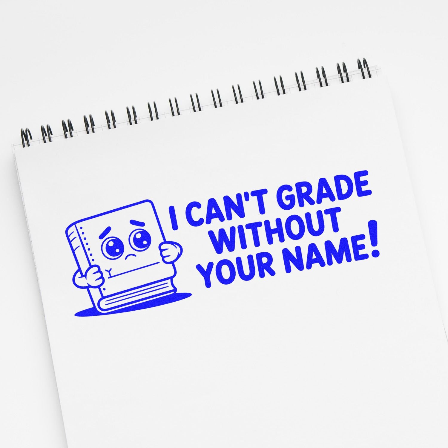 Blue custom teacher stamp/seal on white spiral notebook, cartoon book and bold text I CAN'T GRADE WITHOUT YOUR NAME!