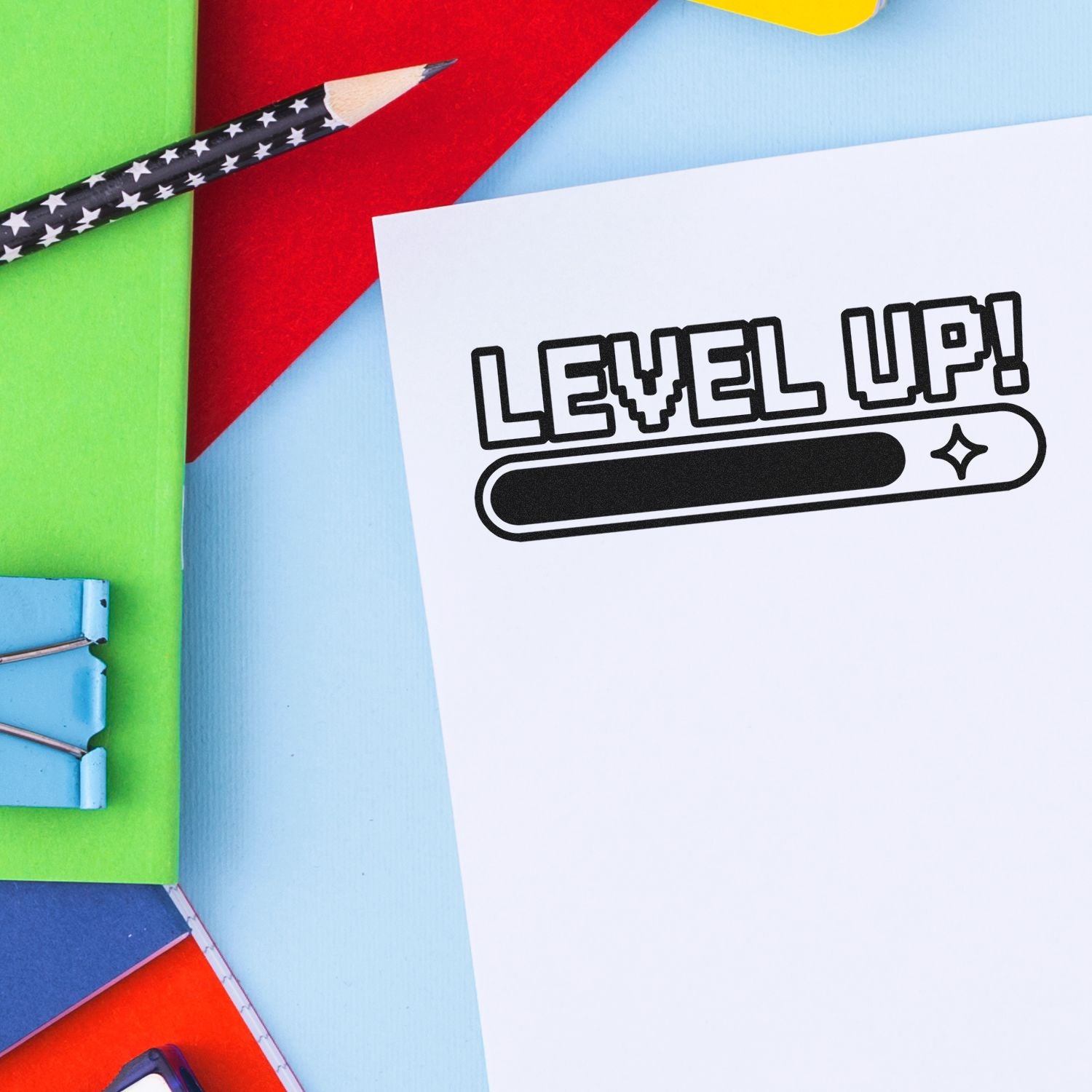 Colorful stamp and seal supplies with LEVEL UP progress graphic on white paper, beside green, red, blue, and yellow stationery.