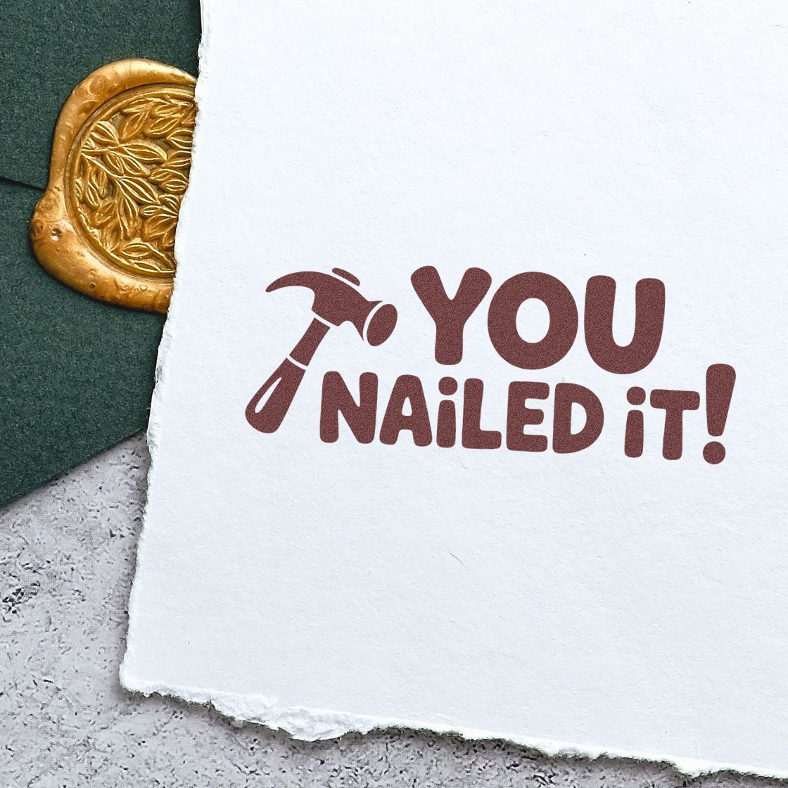 Maroon You Nailed It! stamp with hammer icon on white paper, beside a gold embossed wax seal on dark green.