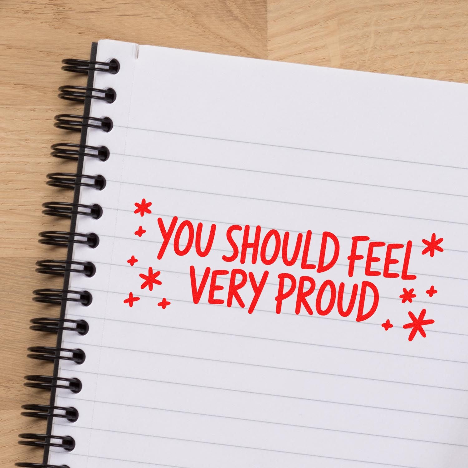 Red custom stamp seal on a lined notebook page reads You should feel very proud with star accents.