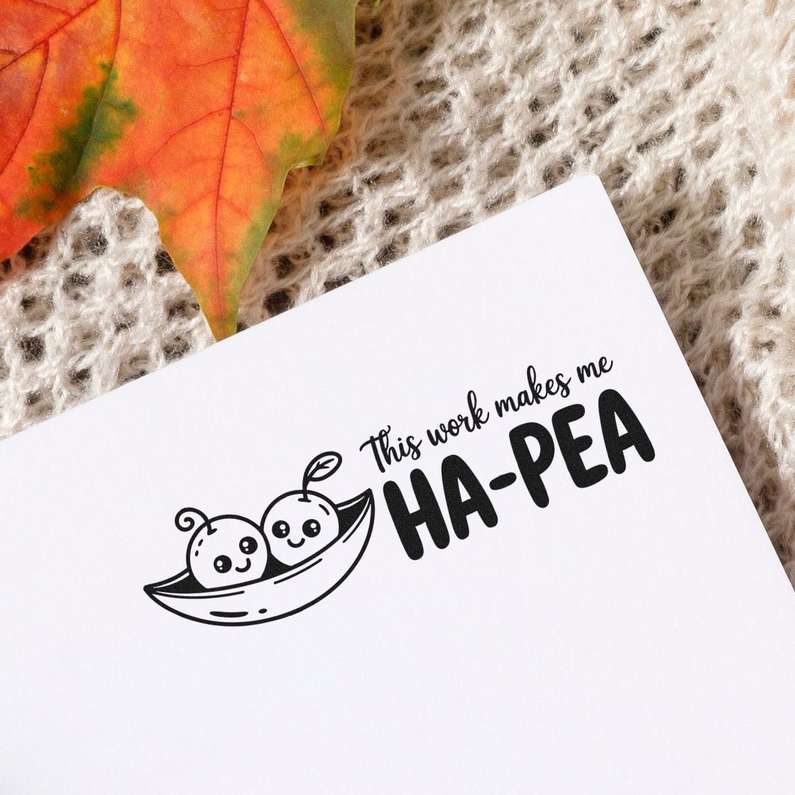 Black stamp and seal on white paper reading This work makes me HA-PEA, with cute pea pod design and orange leaf.