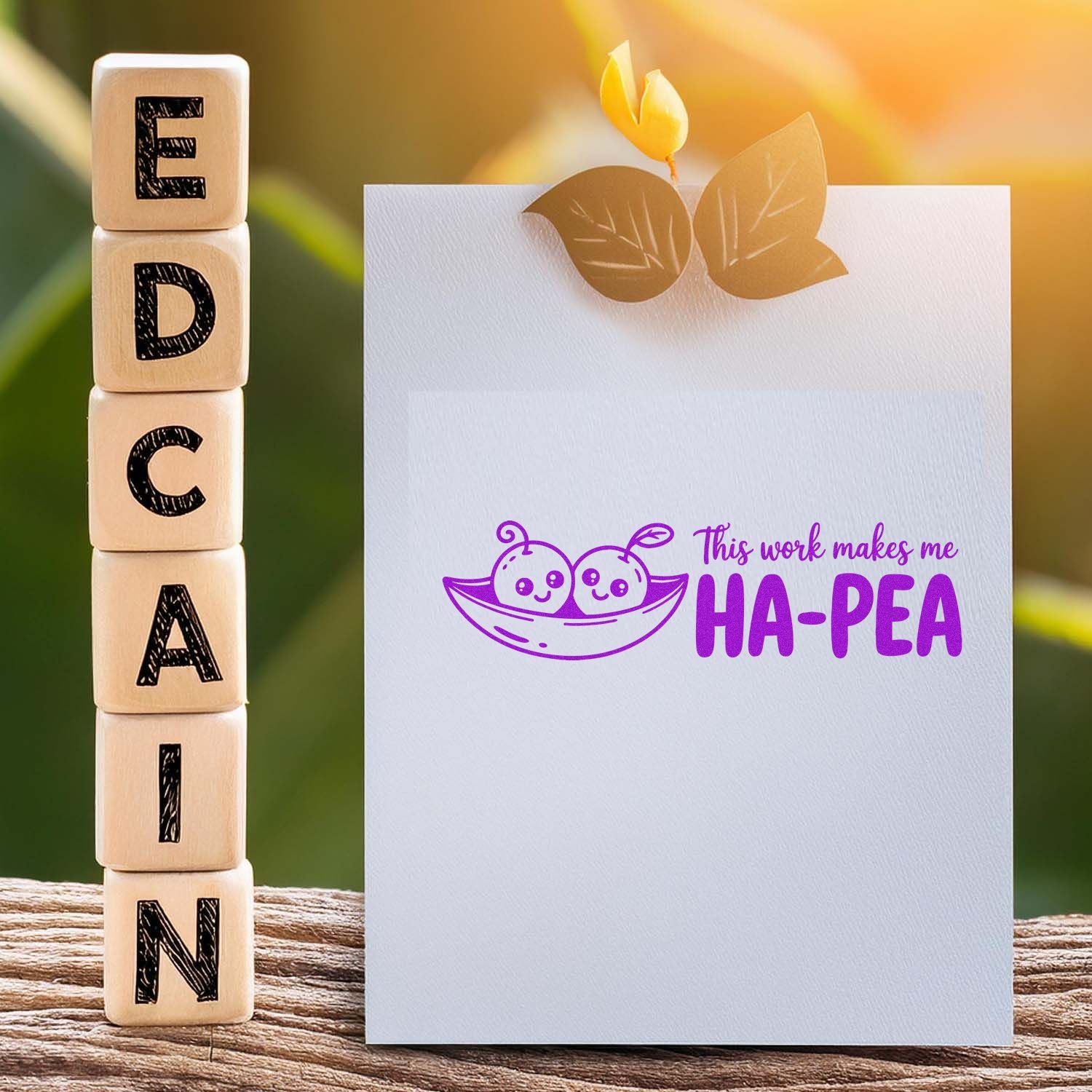 Wooden alphabet stamp blocks beside a white card with purple pea-themed seal and leaf accents in warm golden light.