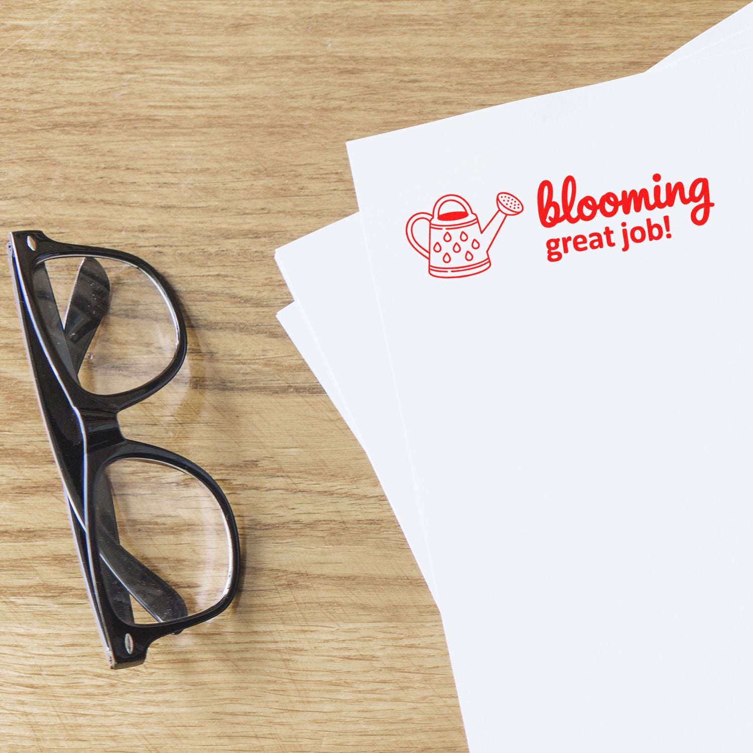 Red blooming great job! stamp and seal with watering can icon on white paper beside black glasses.