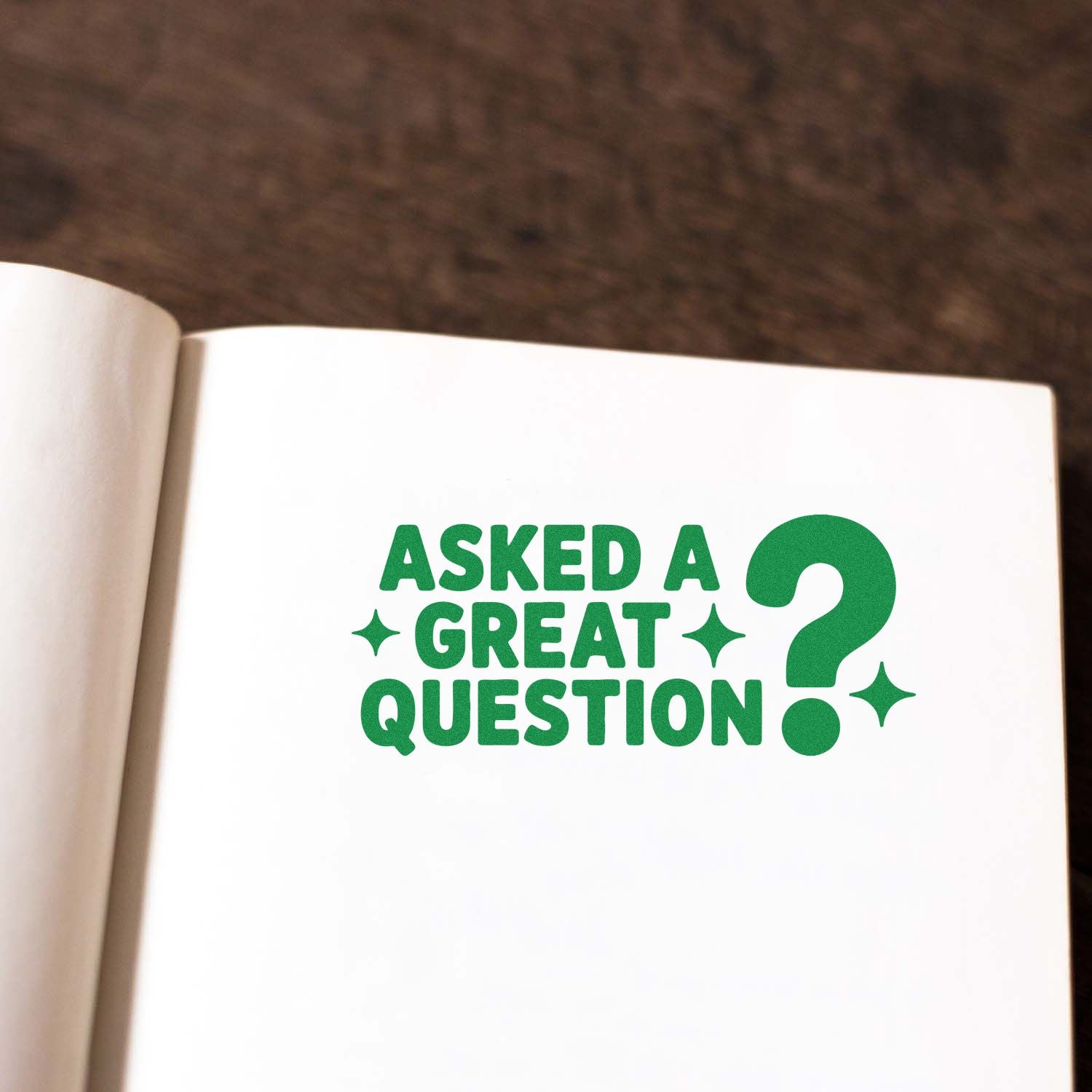 Green stamp seal reading Asked a great question? on a white notebook page with bold green letters and question mark.
