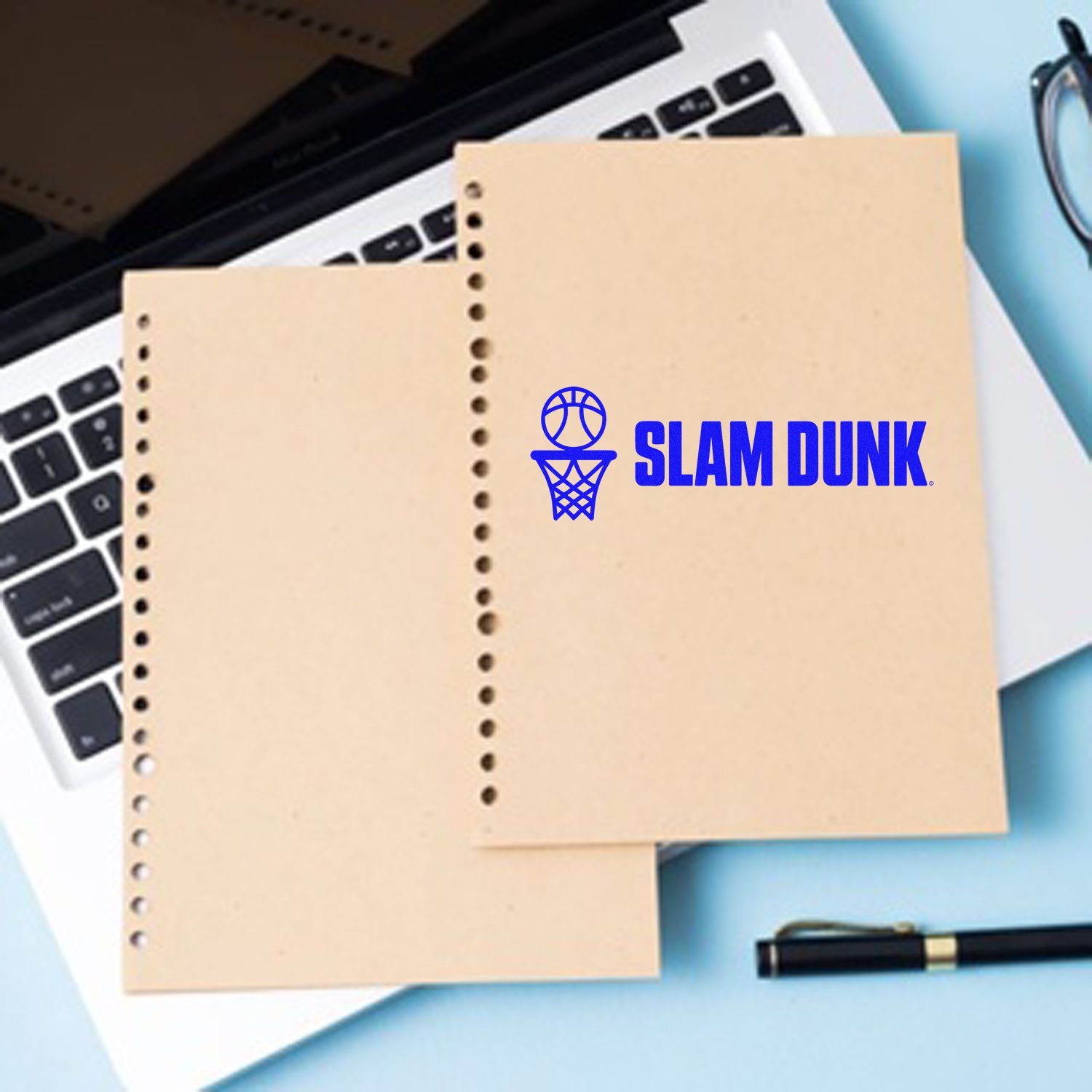 Beige perforated stamp and seal sheets with blue basketball hoop and SLAM DUNK logo on a laptop desk