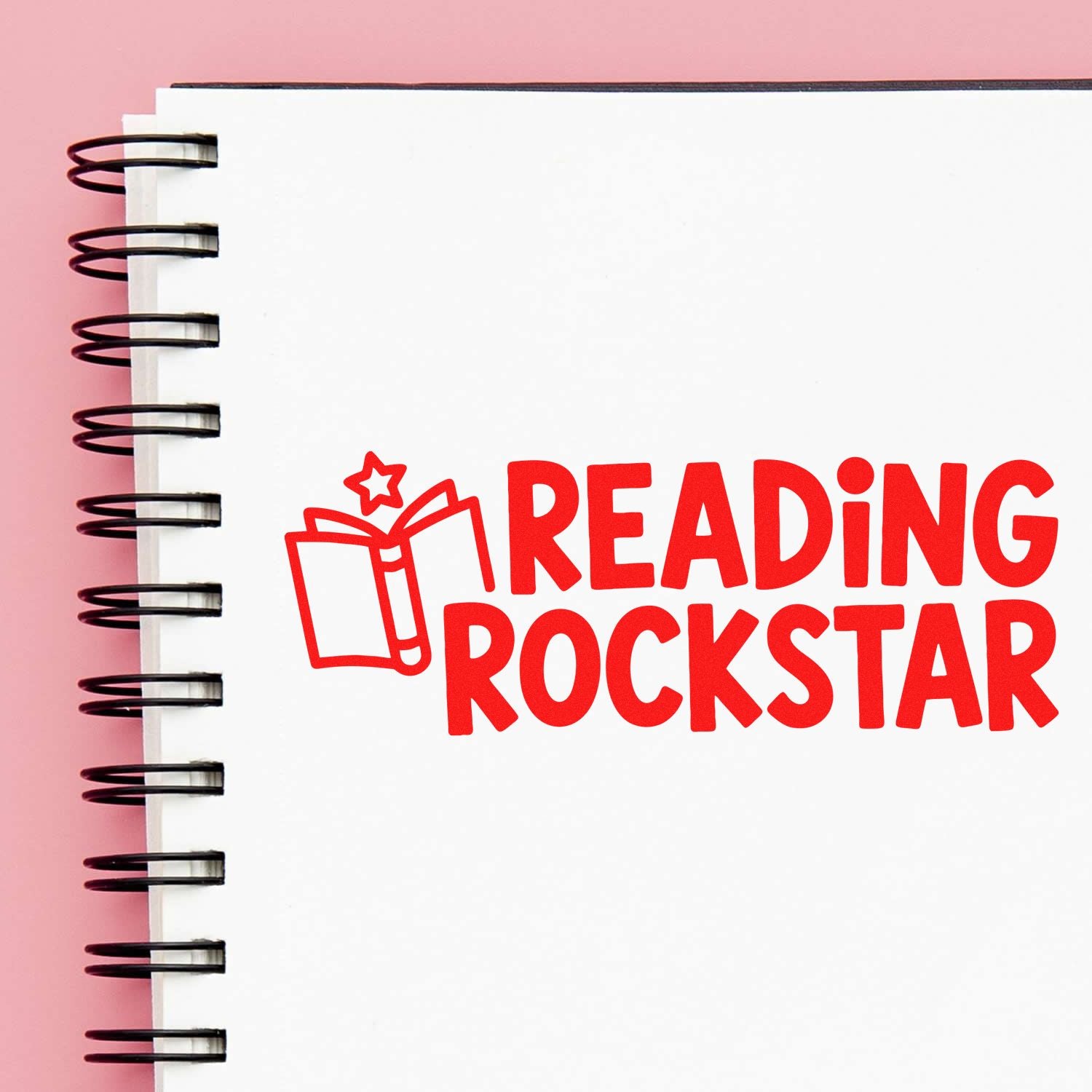Red Reading Rockstar custom stamp with book icon on white spiral notebook, pink background.