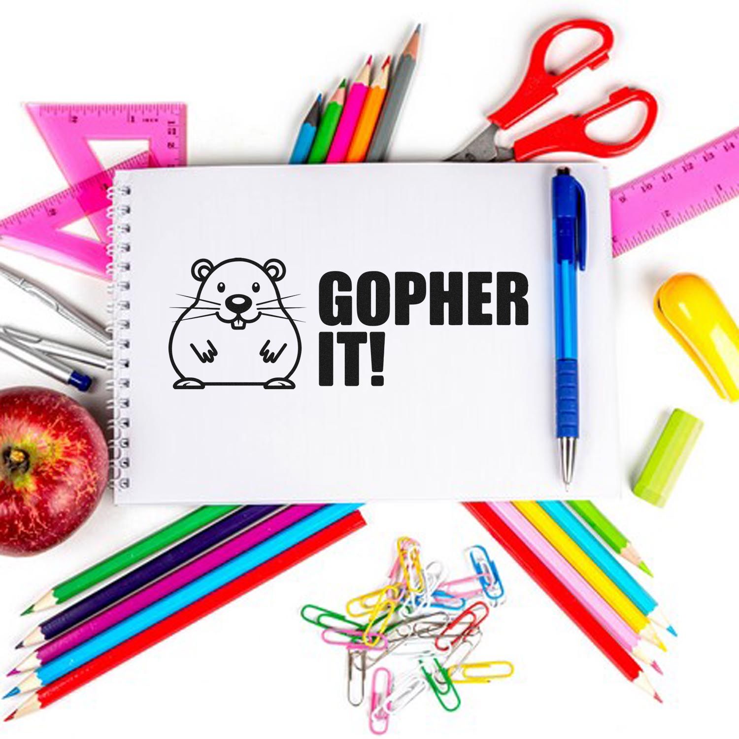 Black Gopher It! stamp and seal on white notebook, surrounded by colorful school supplies, pink rulers, and red scissors.