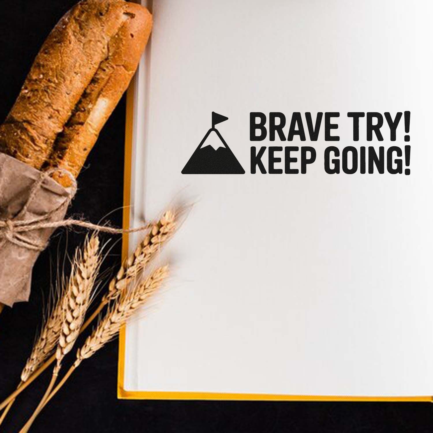 Black custom stamp and seal on white paper: mountain flag icon with BRAVE TRY! KEEP GOING! beside rustic bread and wheat.