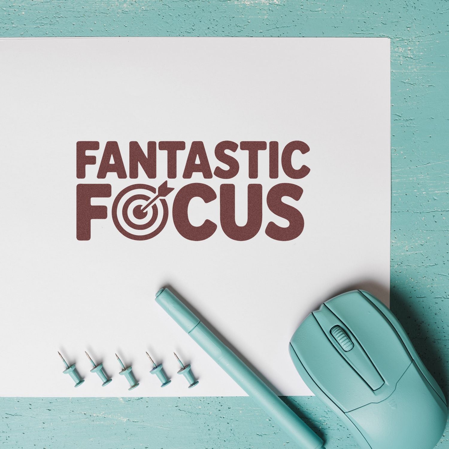 Maroon Fantastic Focus stamp design on white paper with teal stamp, pen, and embossing seal tools on turquoise background.