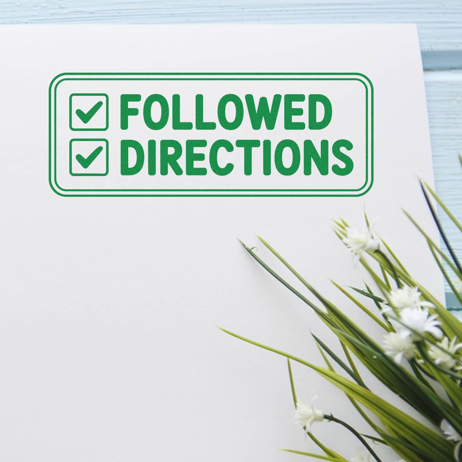 Green rubber stamp seal reading Followed Directions with two checkboxes and check marks on white paper.