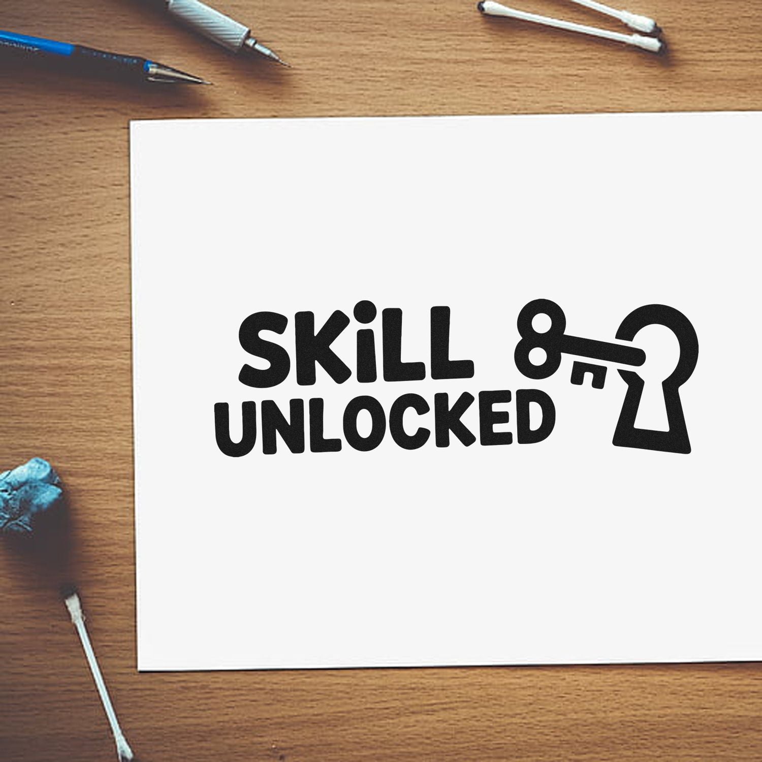 Black Skill Unlocked stamp and keyhole seal on white paper, with blue tools on a wood desk.