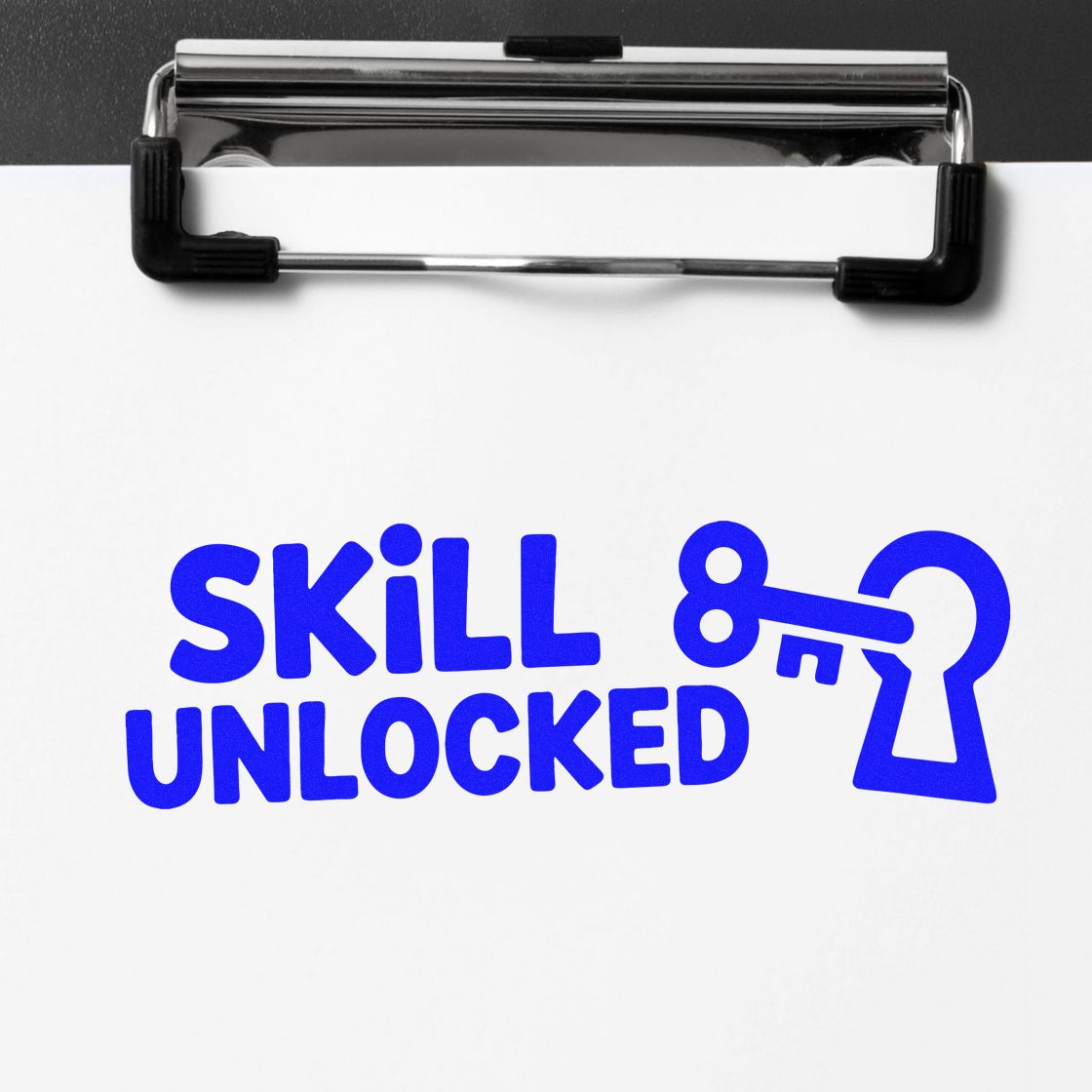 Blue custom stamp imprint reading Skill Unlocked with key and lock icon on white paper, clipped to a black clipboard.