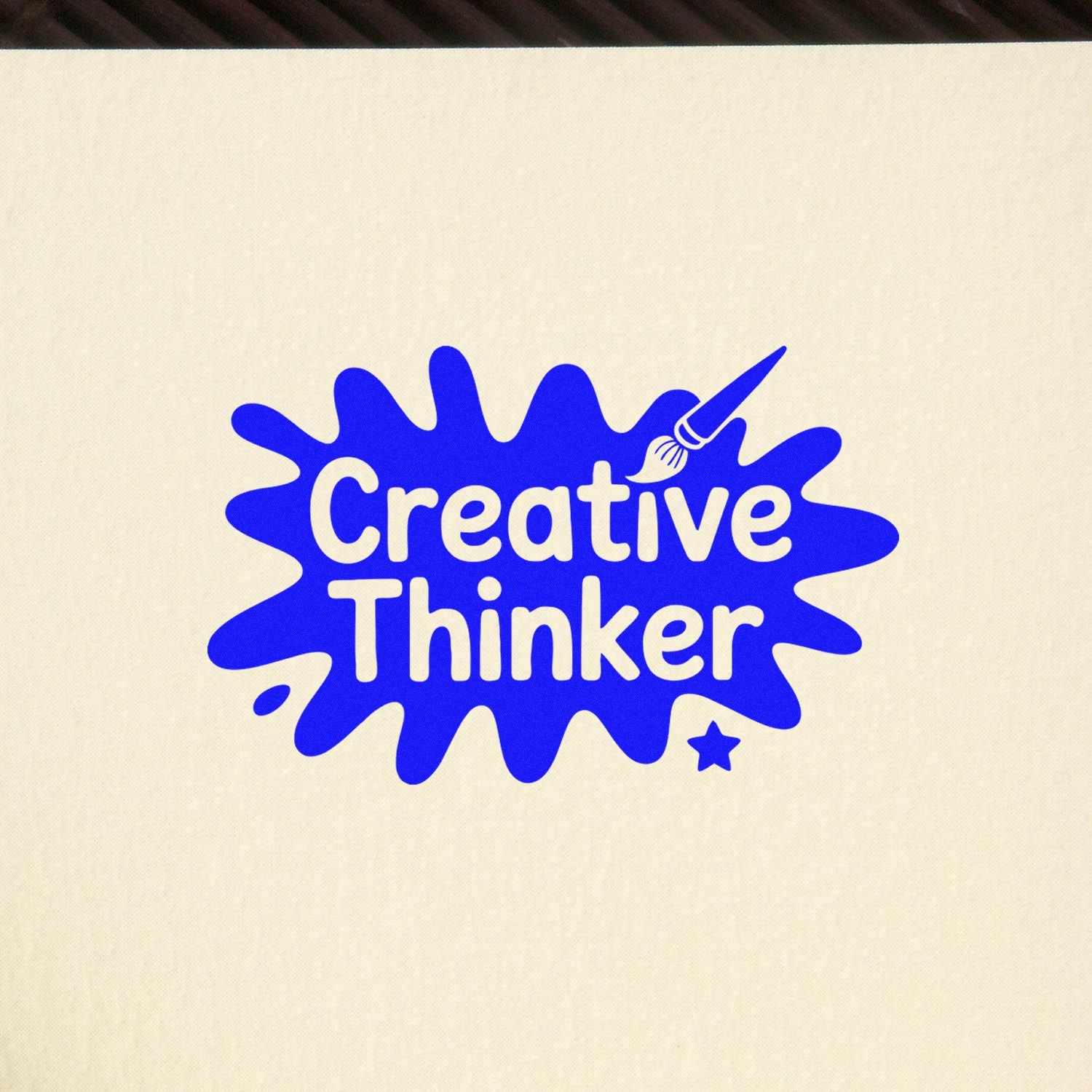 Blue Creative Thinker stamp seal with paintbrush and star in bright blue on a cream background.