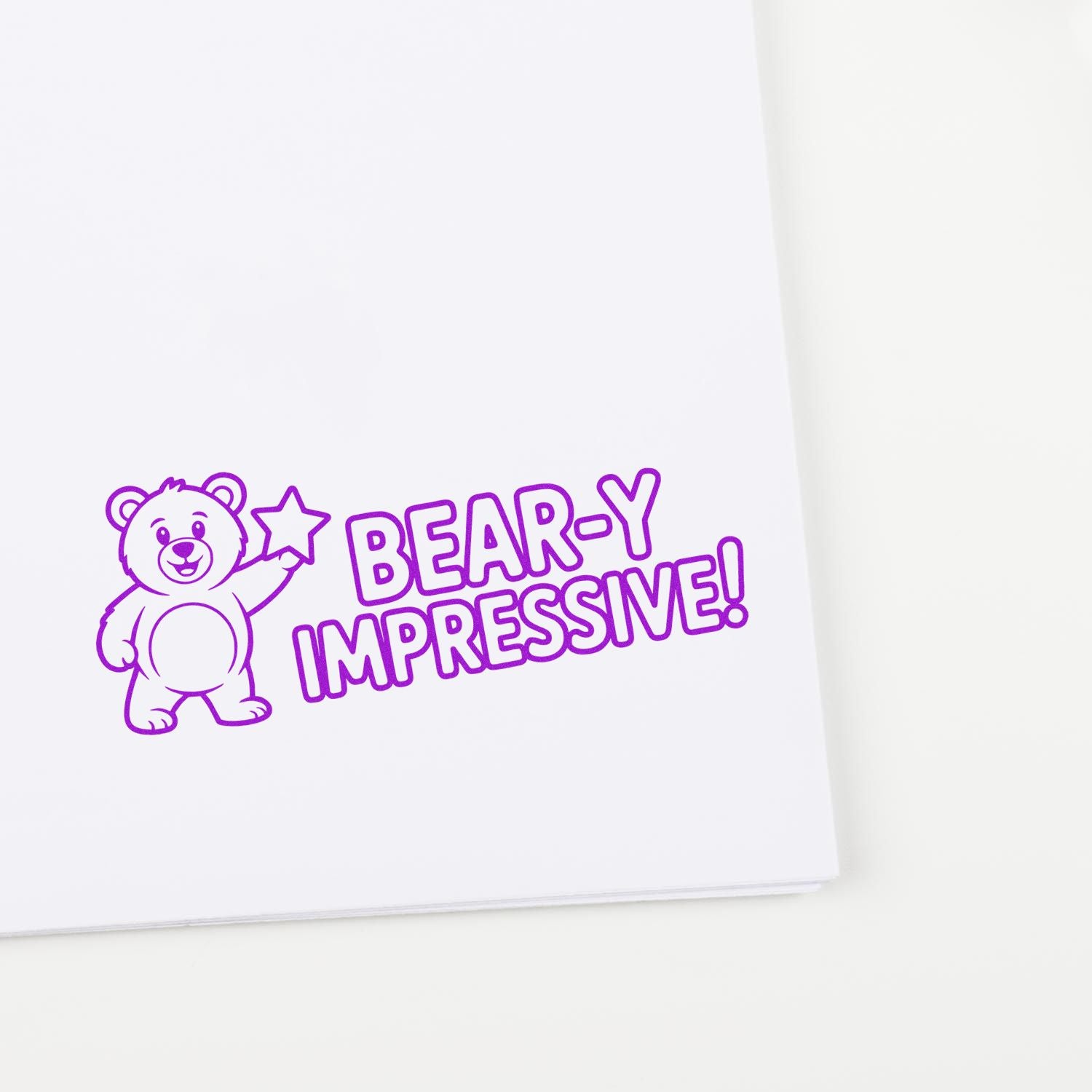 Purple bear rubber stamp seal with star and BEAR-Y IMPRESSIVE! text on white paper.
