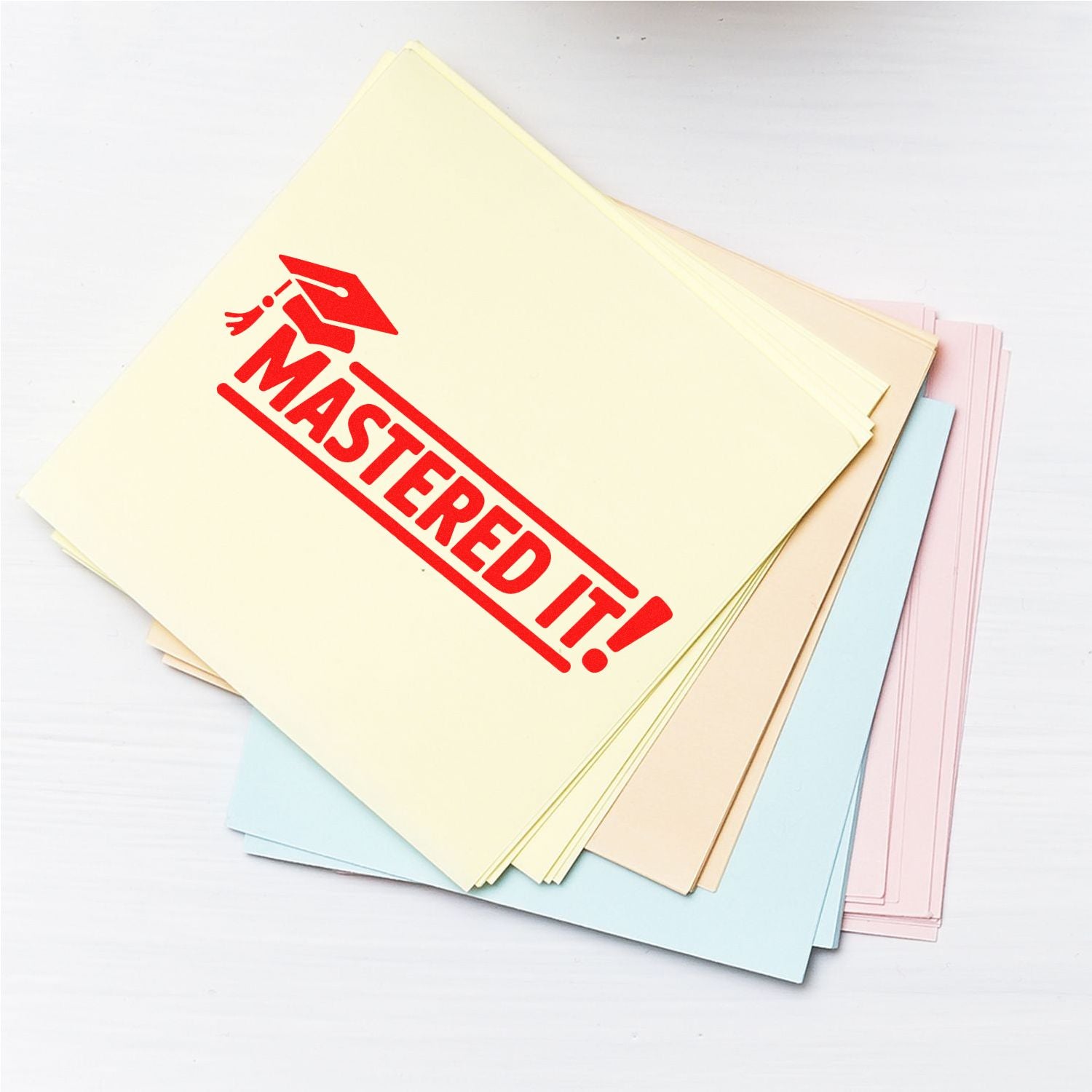 Stack of pastel paper sheets with red MASTERED IT! graduation stamp seal on top