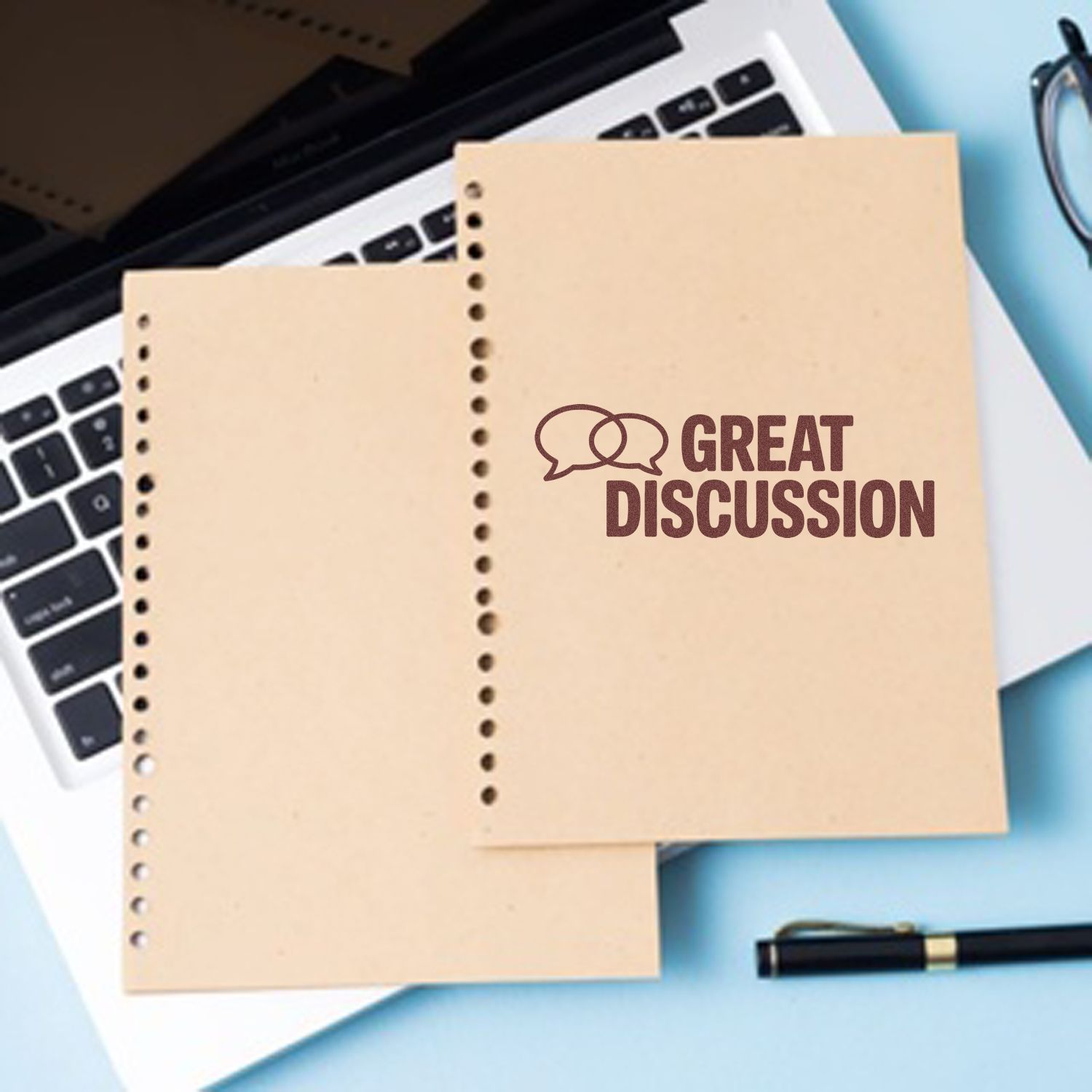 Beige perforated sheets with maroon Great Discussion stamp seal on a blue desk over a laptop and pen.
