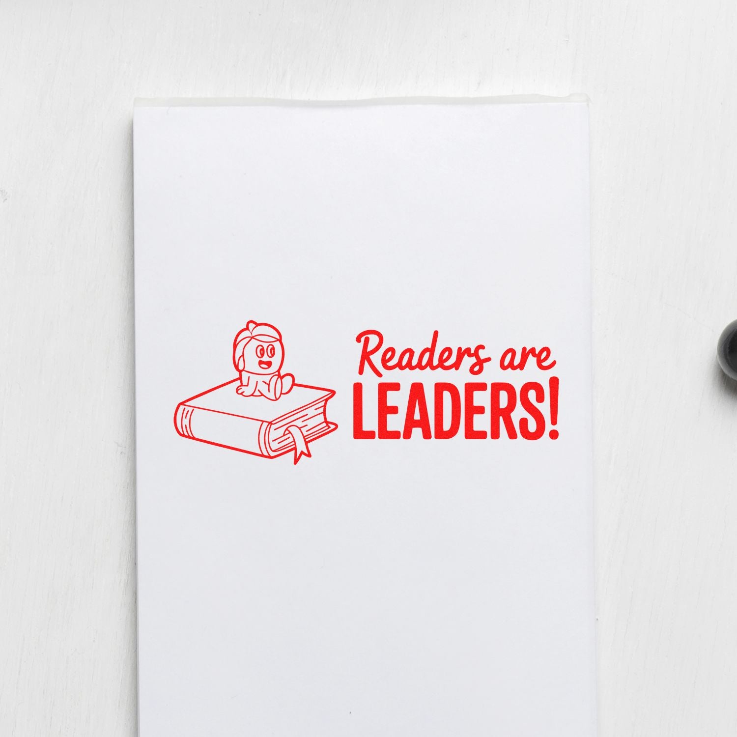 Red stamp and seal design with bookworm on book and Readers are Leaders! text on white paper.