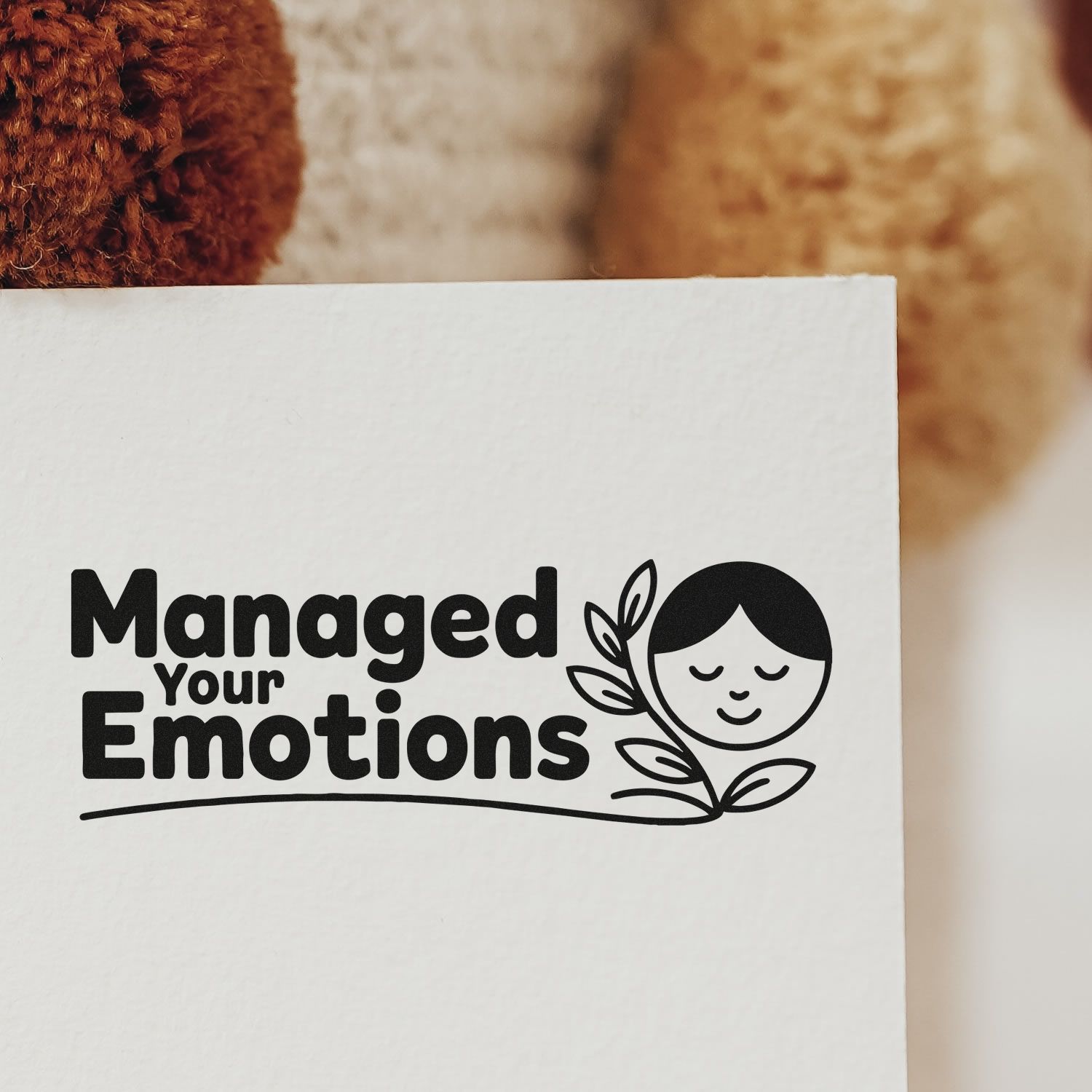 Black custom stamp seal reading Managed Your Emotions with a calm face and leaf graphic on white paper.