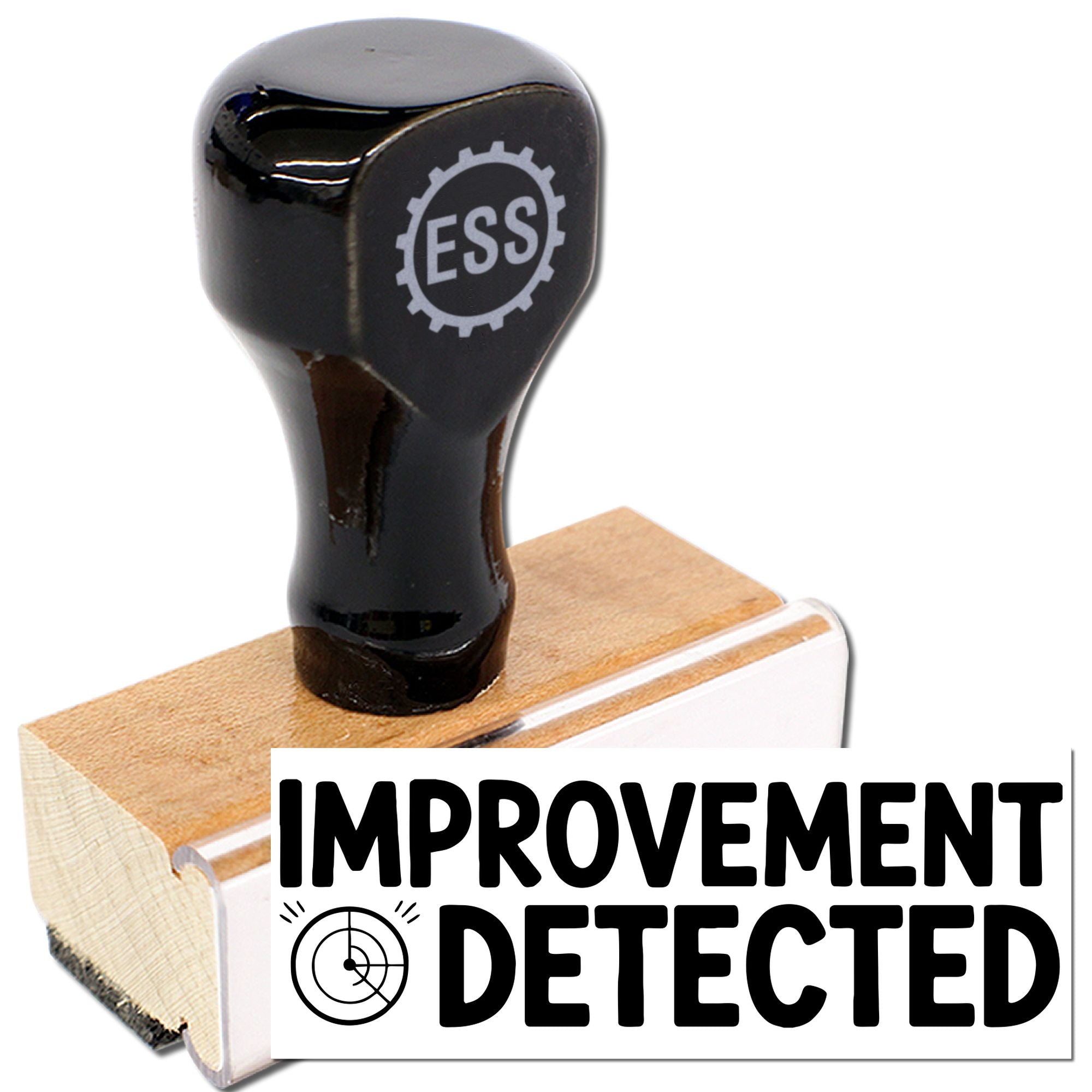 Black rubber stamp seal on wooden block with ESS gear logo and bold IMPROVEMENT DETECTED text.