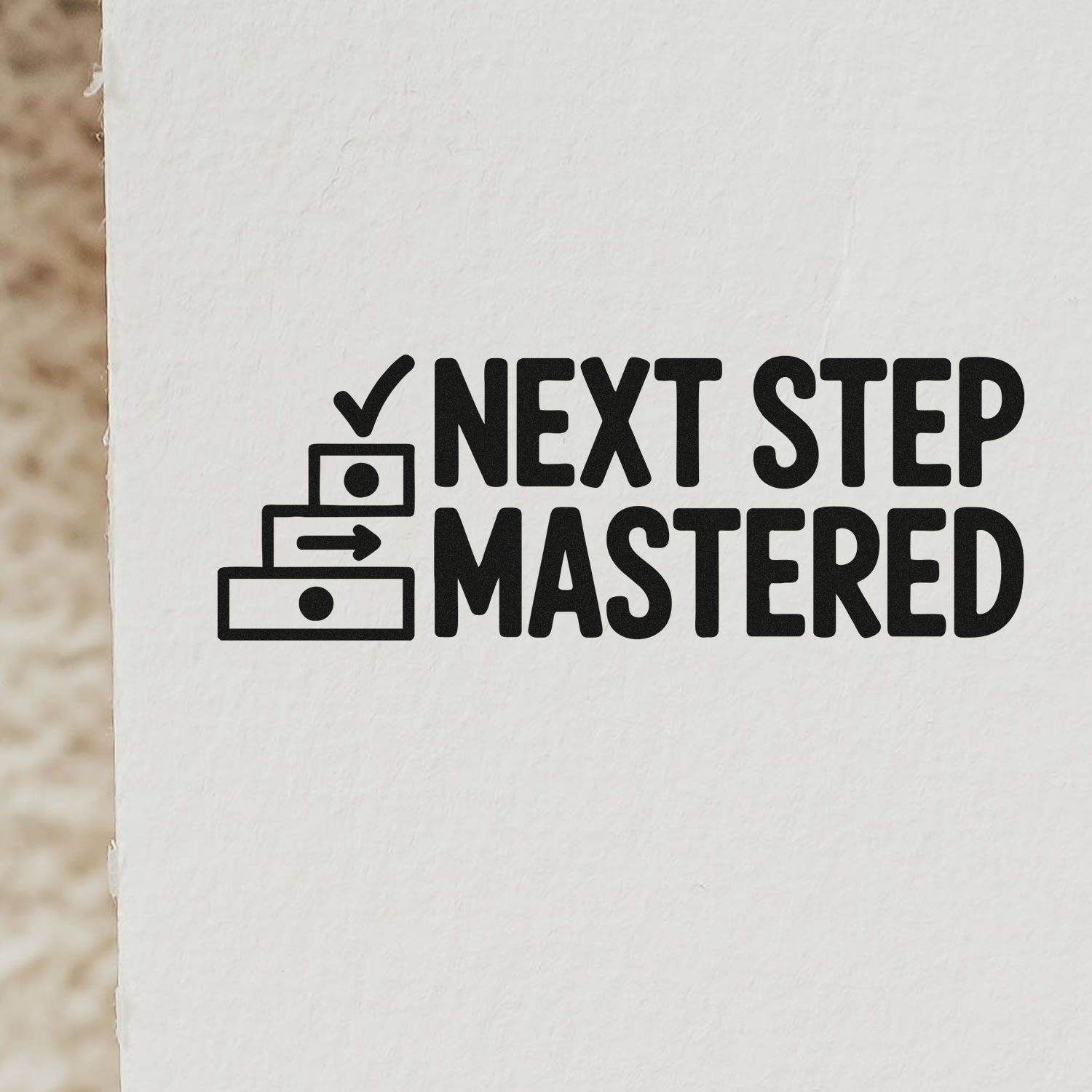 Black Next Step Mastered stamp and seal design with checkmark, arrow, and drawer icon on white textured paper.