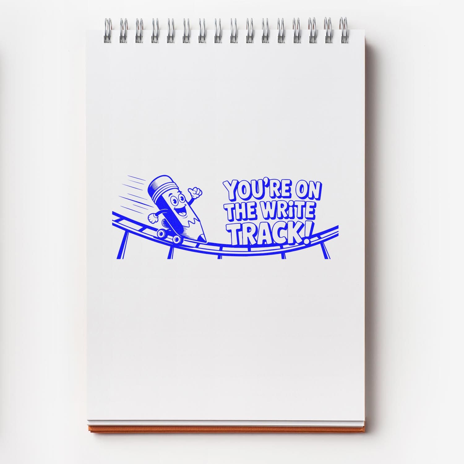 Blue custom stamp and seal design on white notepad with pencil on track and Youre on the write track! text.