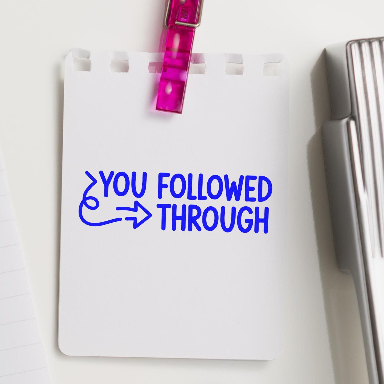 Blue You Followed Through stamp on white card with pink clip seal and silver stamp tool beside it.