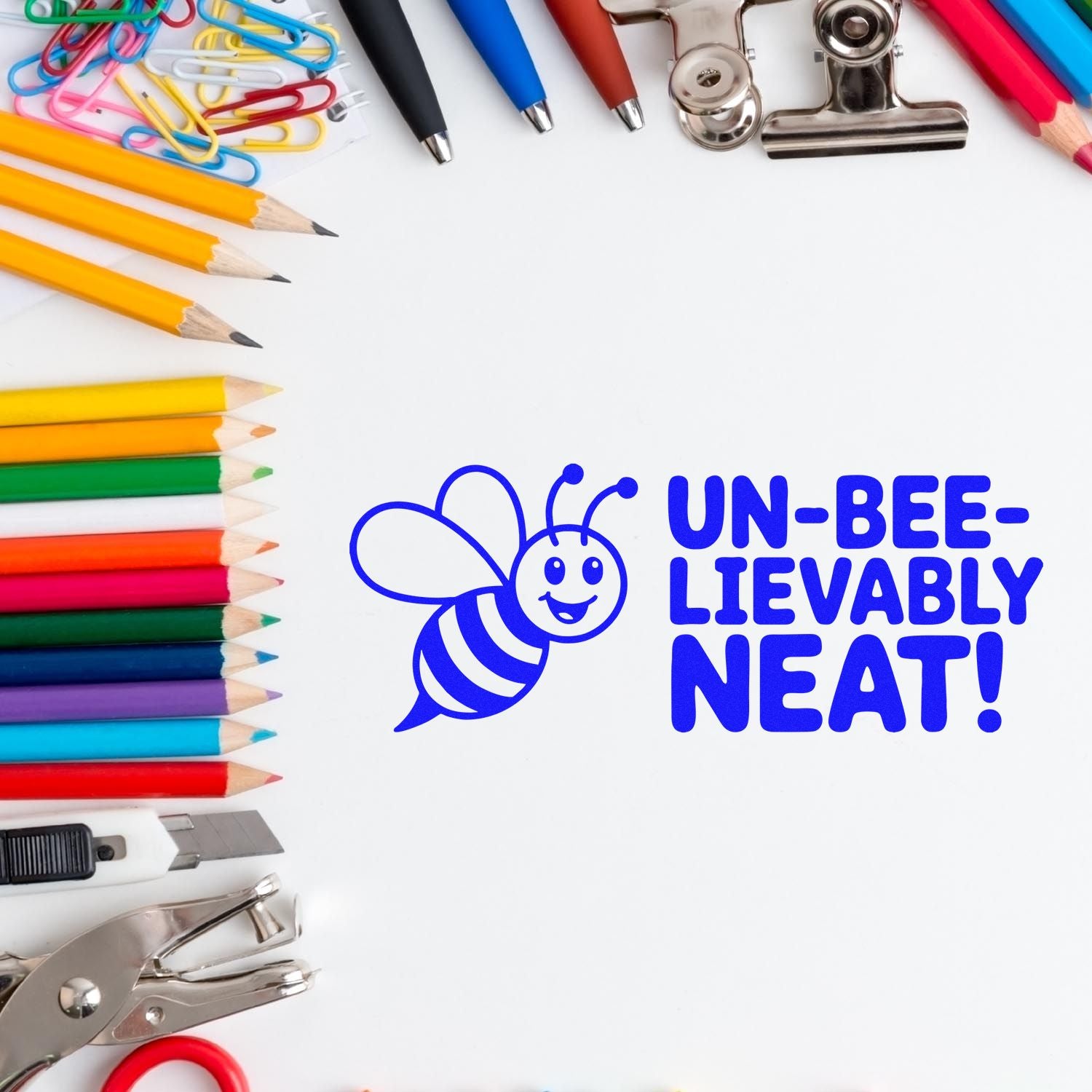 Blue bee stamp with Un-bee-lievably neat text, framed by colorful pencils, clips, a utility knife, and a metal seal punch.