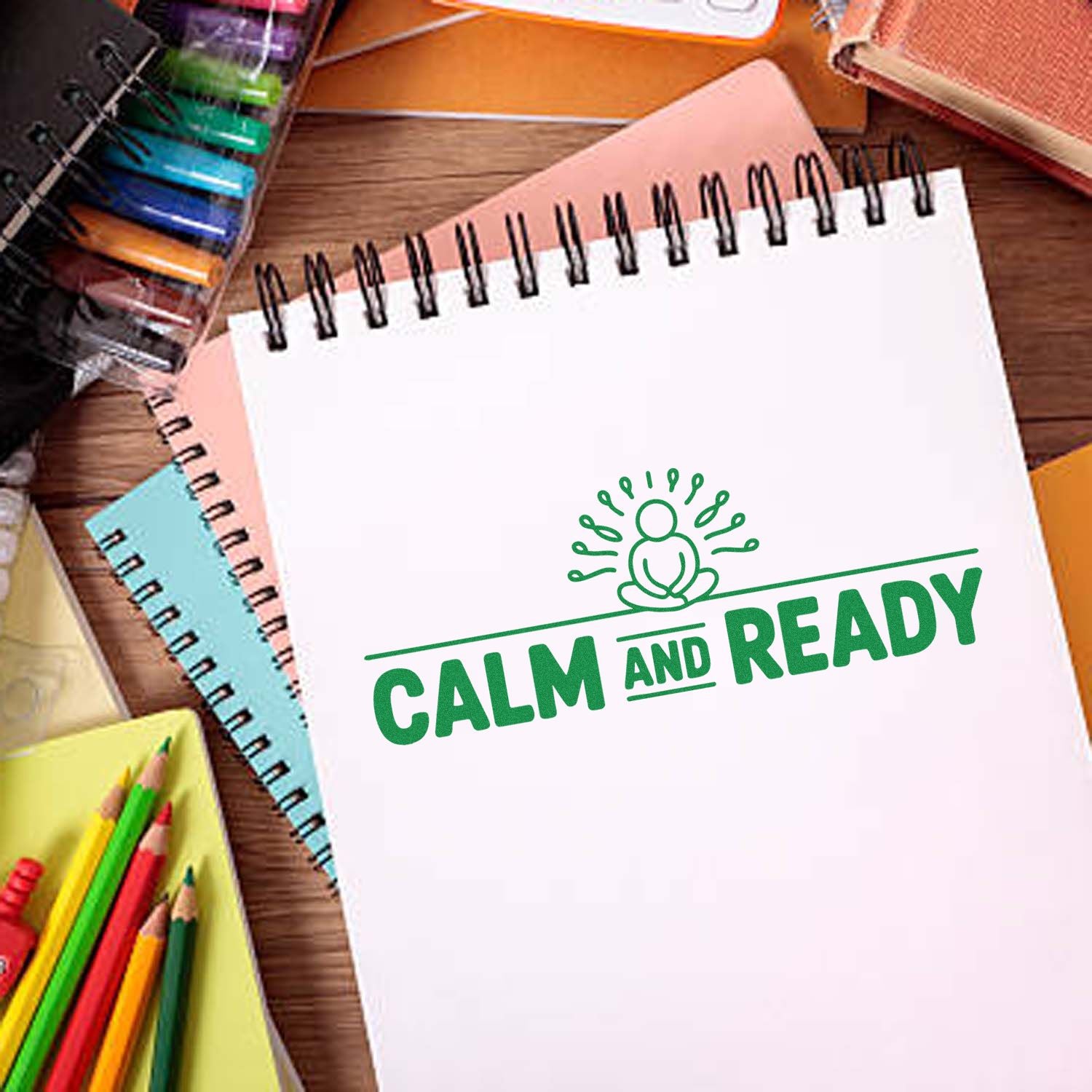 Green Calm and Ready stamp seal on a white spiral notebook, surrounded by colorful stationery on a wooden desk.