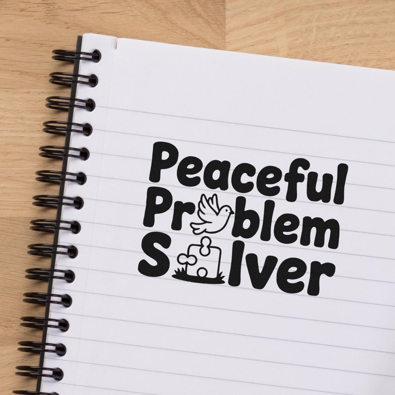 Black stamp-and-seal design reading Peaceful Problem Solver with dove and puzzle-piece icons on white notebook.