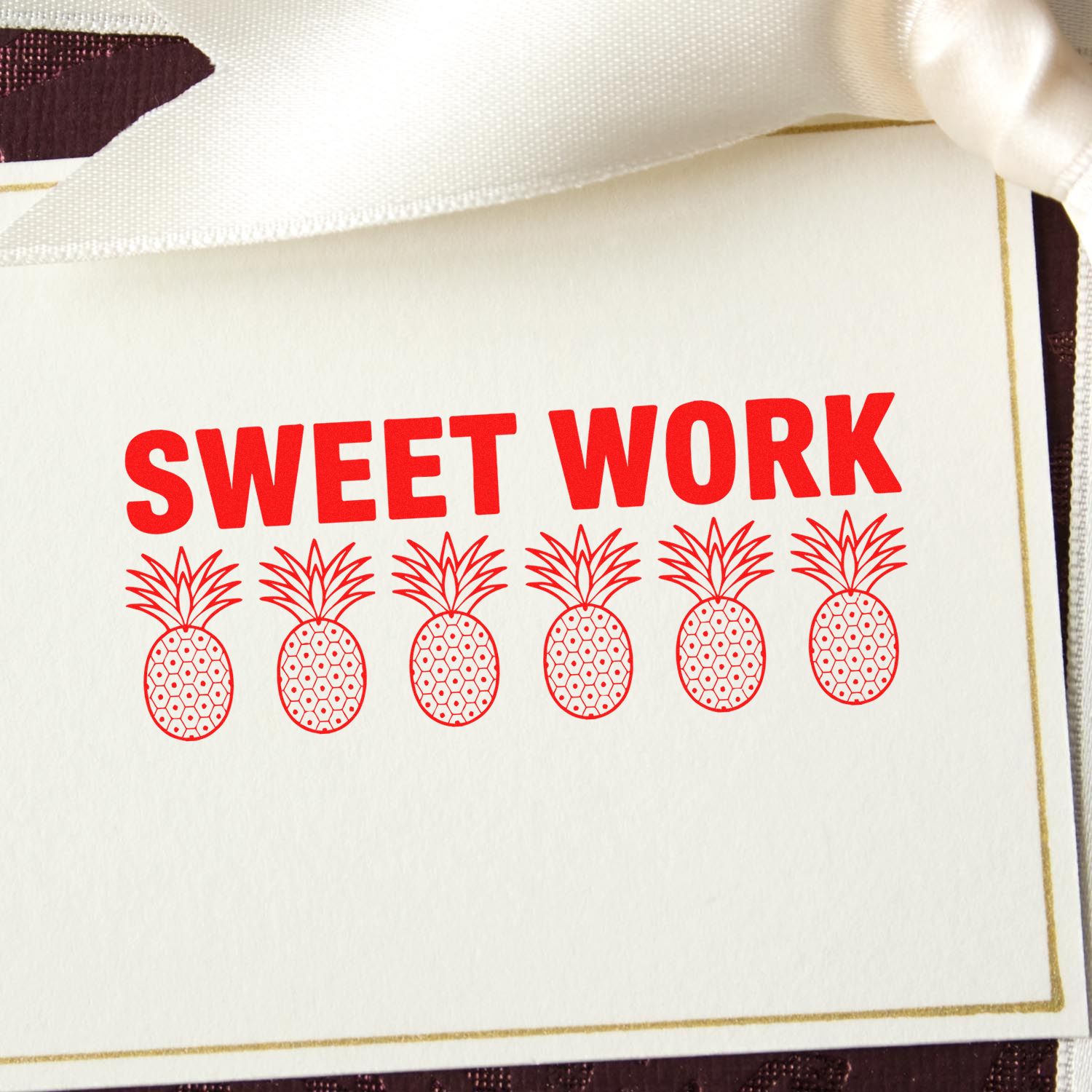 Red Sweet Work stamp seal on white card with six pineapple motifs and gold border, tied with white ribbon.