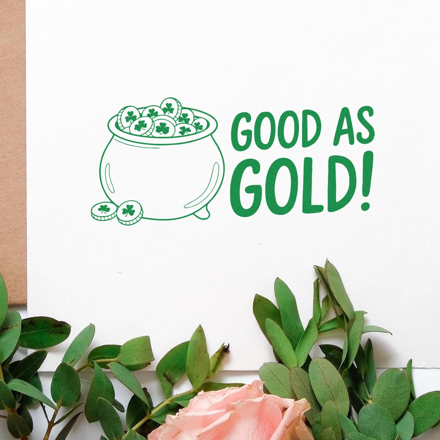 Green stamp and seal design with a pot of gold, shamrock coins, and GOOD AS GOLD! on a white card.