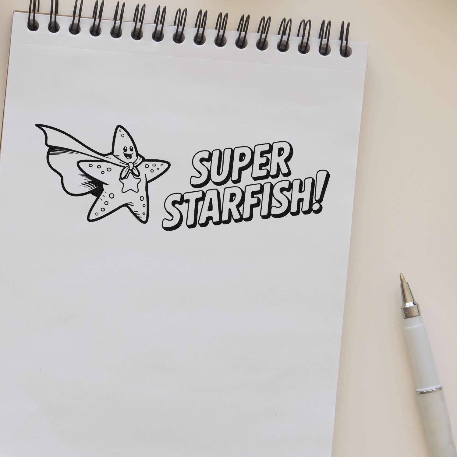 Black-and-white stamp/seal design of a smiling superhero starfish with SUPER STARFISH! on a spiral notepad.
