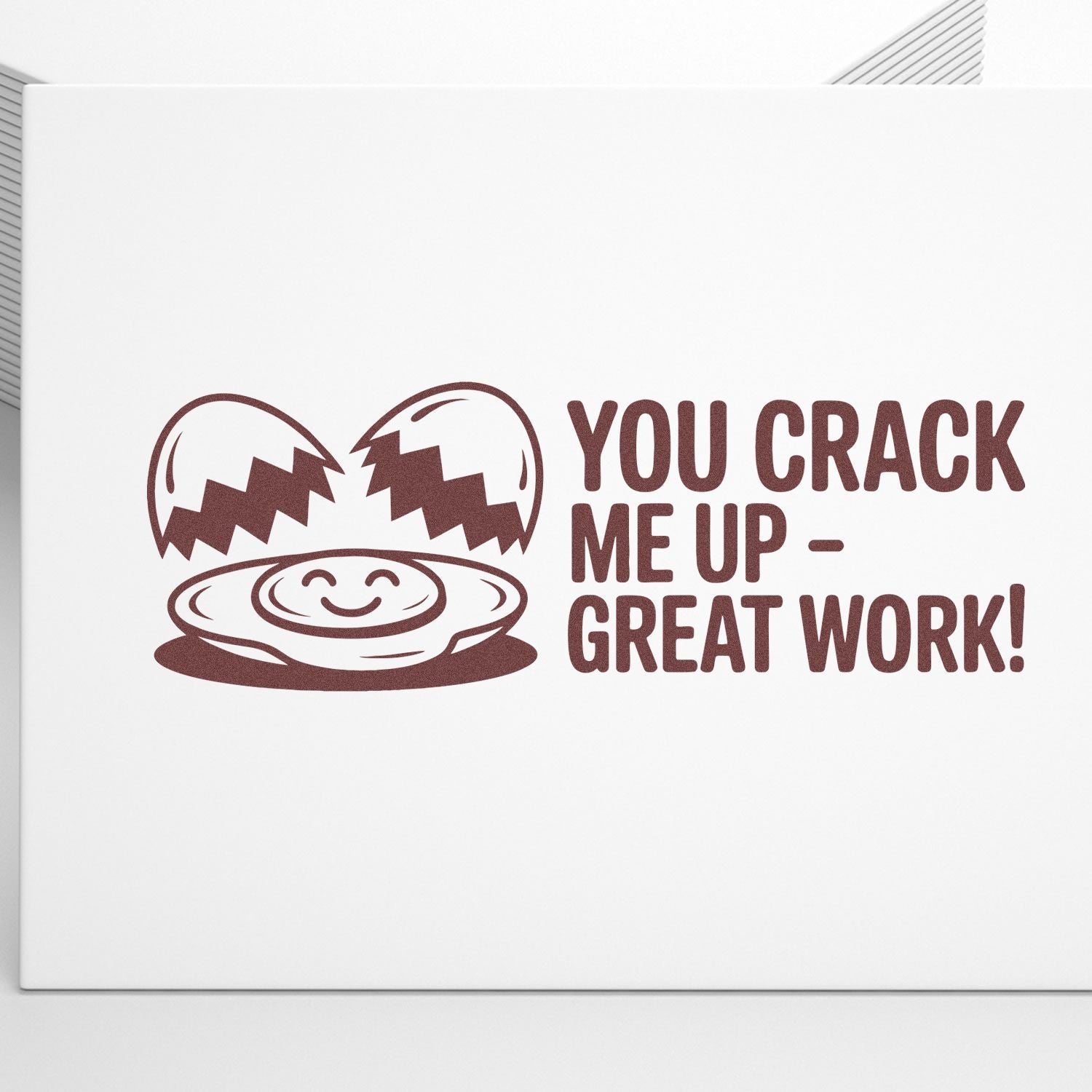 Brown stamp seal with cracked egg and smiling yolk saying YOU CRACK ME UP - GREAT WORK! on white background.