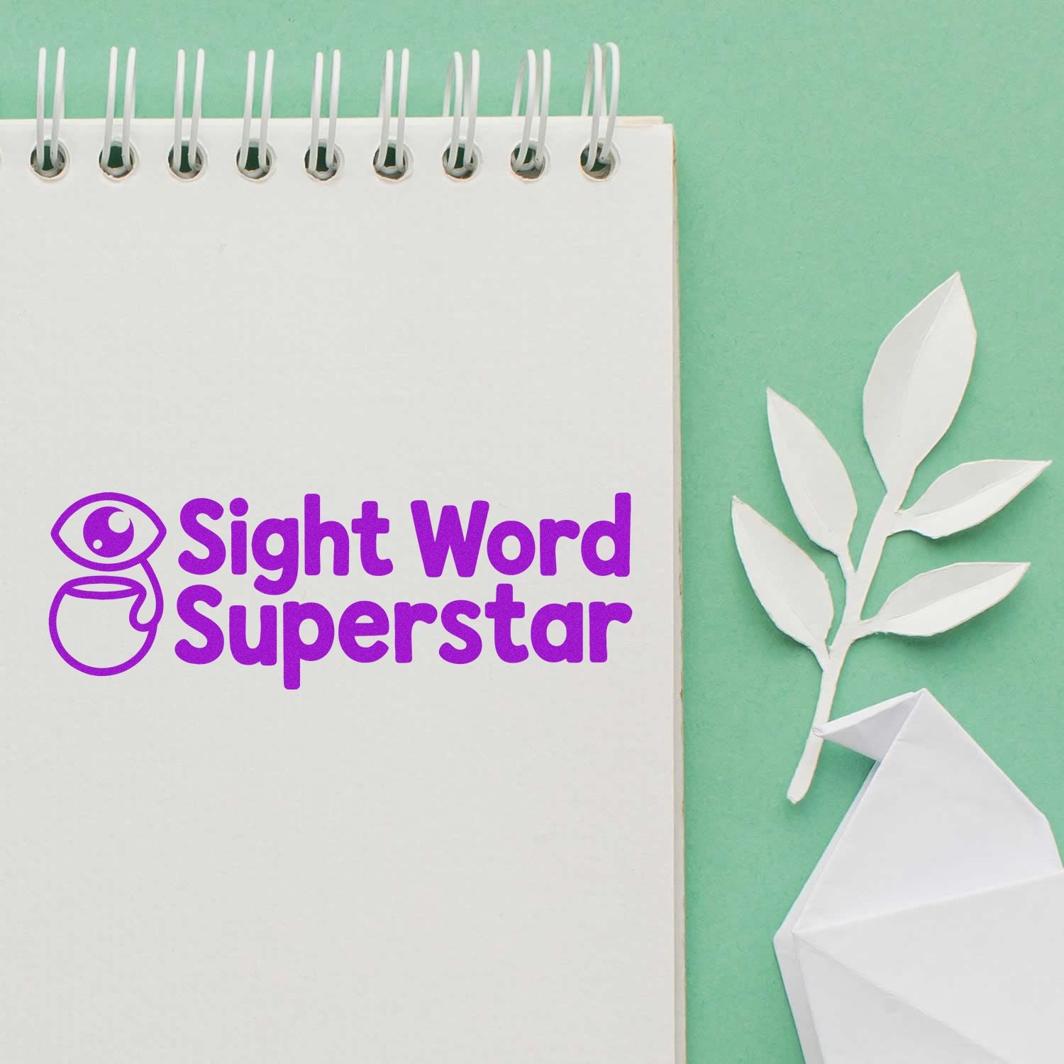 Purple Sight Word Superstar stamp and seal on a white spiral notebook, with mint green background and white paper leaves.
