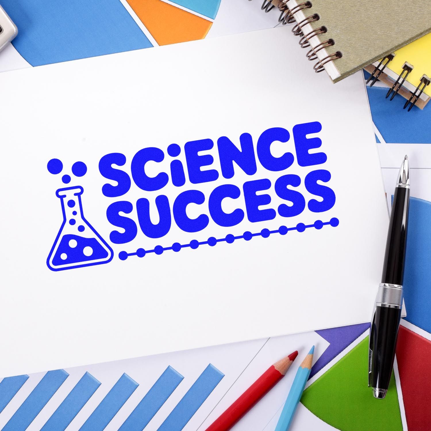 Blue Science Success stamp and seal with flask icon on white paper, surrounded by colorful notebooks, pens, and swatches.