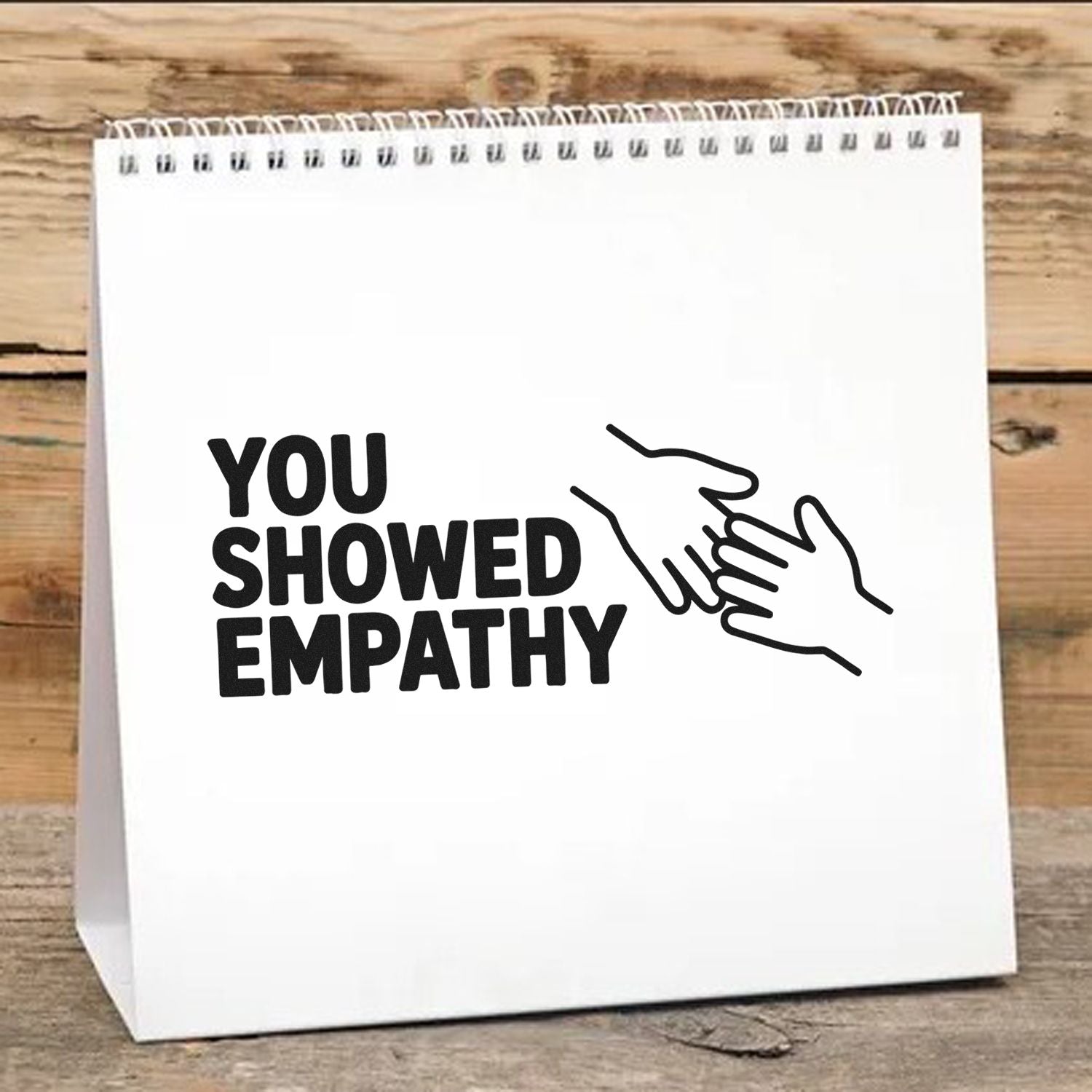 White stamp-and-seal bag with black You Showed Empathy text and handshake graphic on rustic wood.