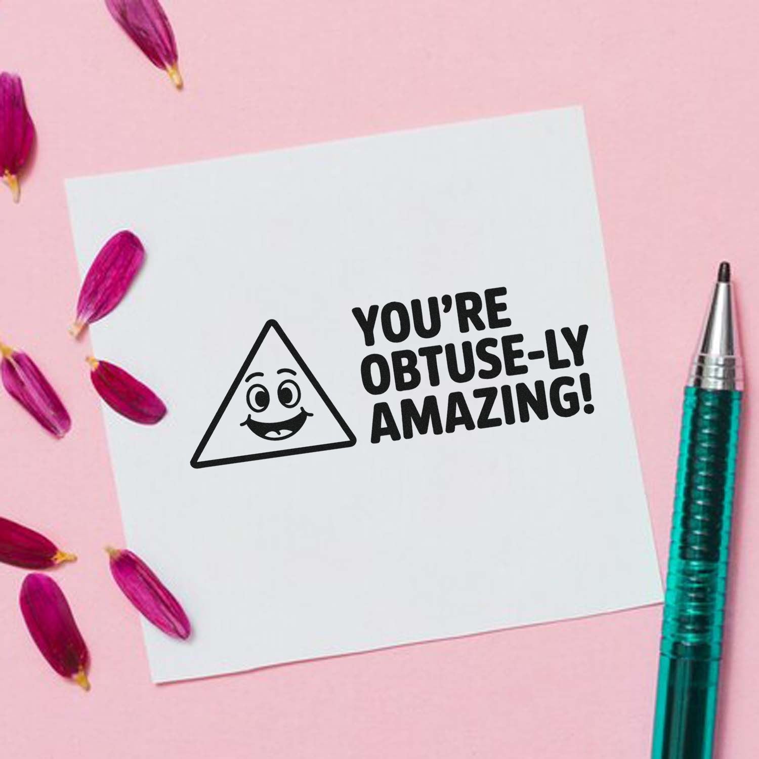 Black stamp and seal reading Youre obtuse-ly amazing! on white card, with triangle face, pink petals, and teal pen.
