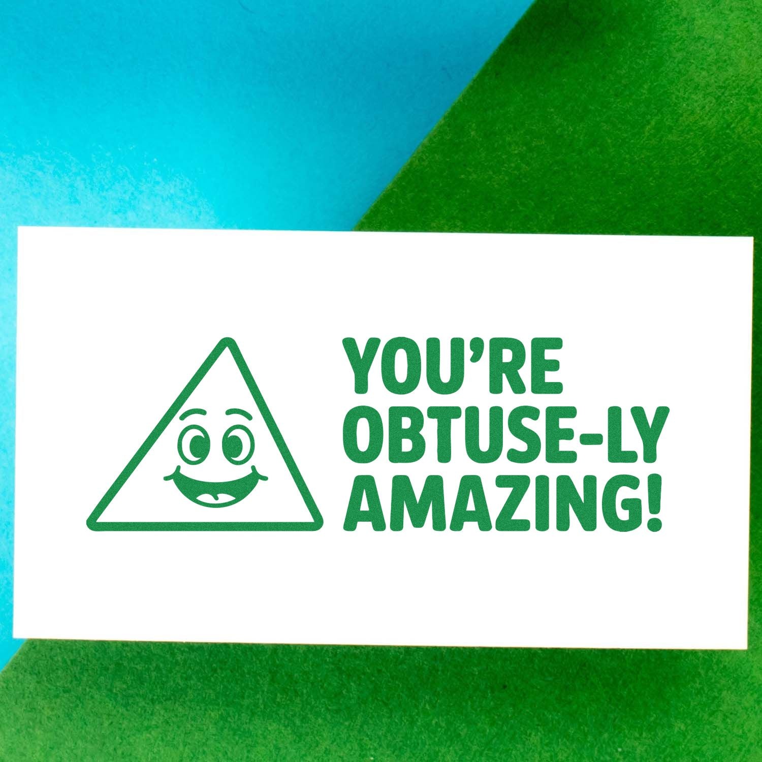 Green stamp and seal design with smiling triangle and Youre obtuse-ly amazing! on a white card over blue and green background.