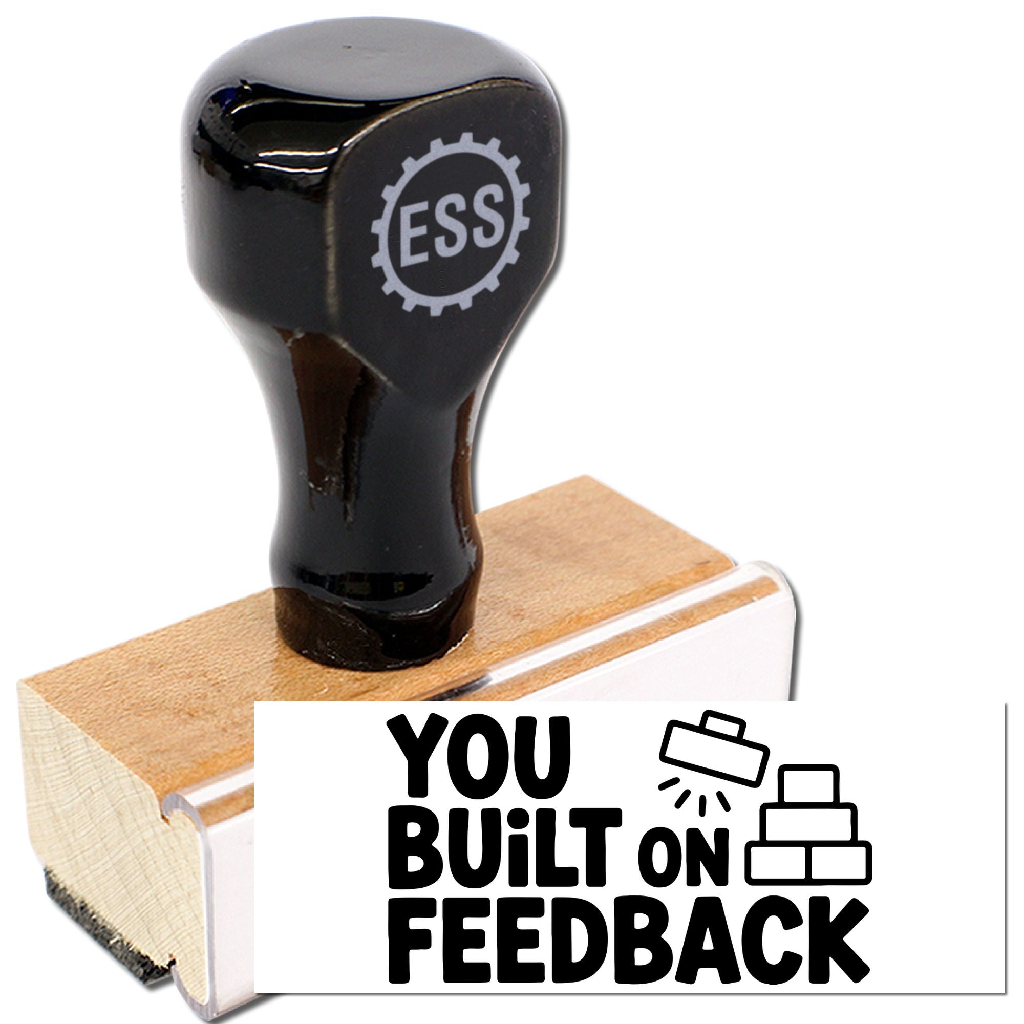Black stamp and seal handle on a wooden block with a white label and bold black You Built on Feedback text.
